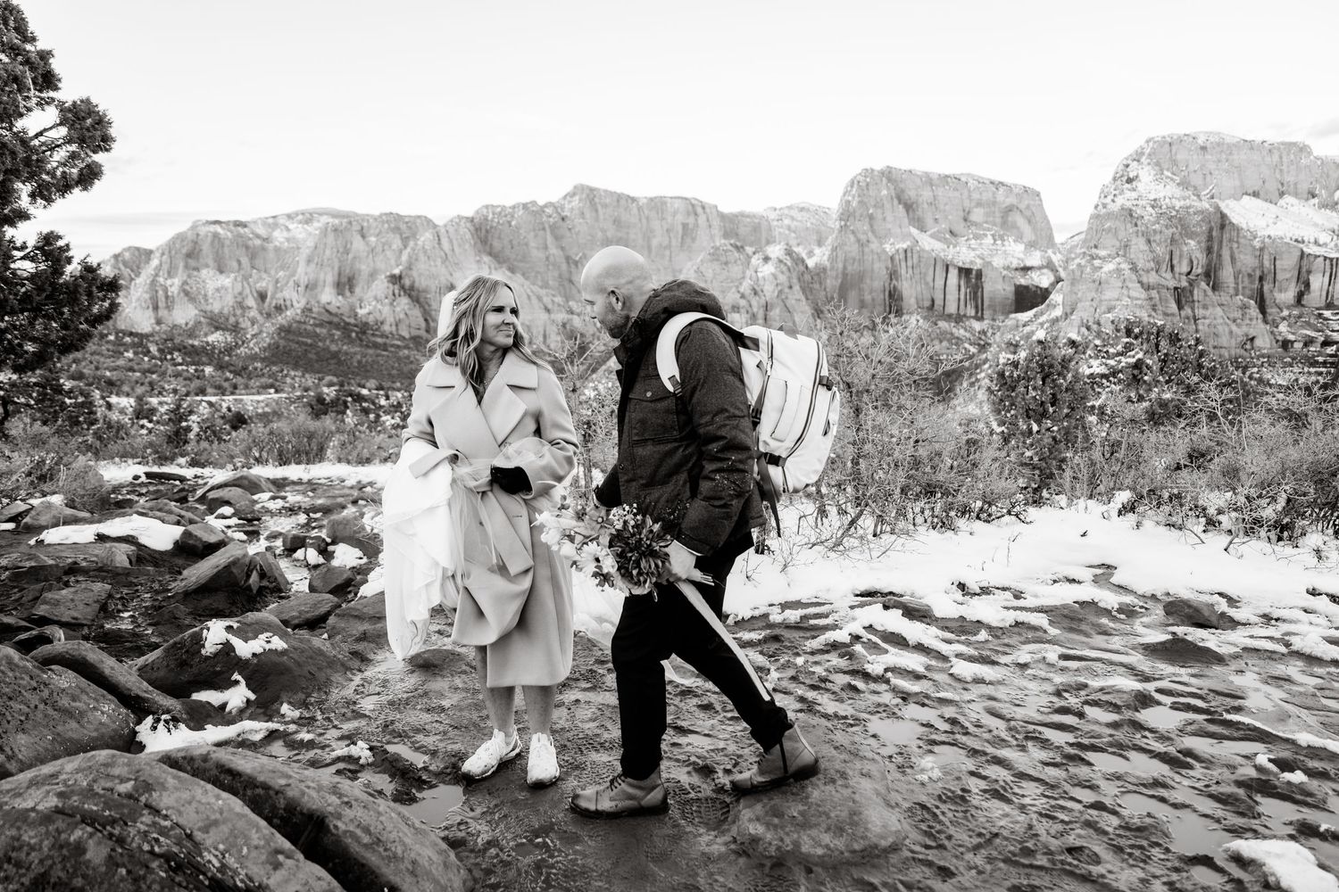 Black and white photo of couple exploring snowy canyon landscape.