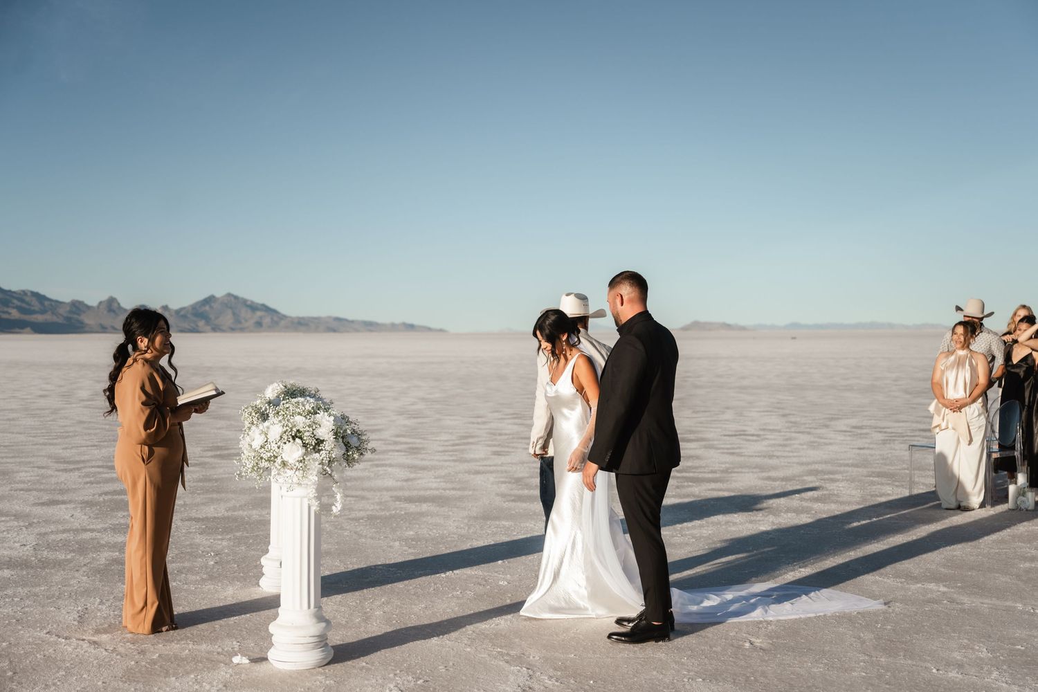 Wedding ceremony setup on vast salt flats with mountain backdrop.