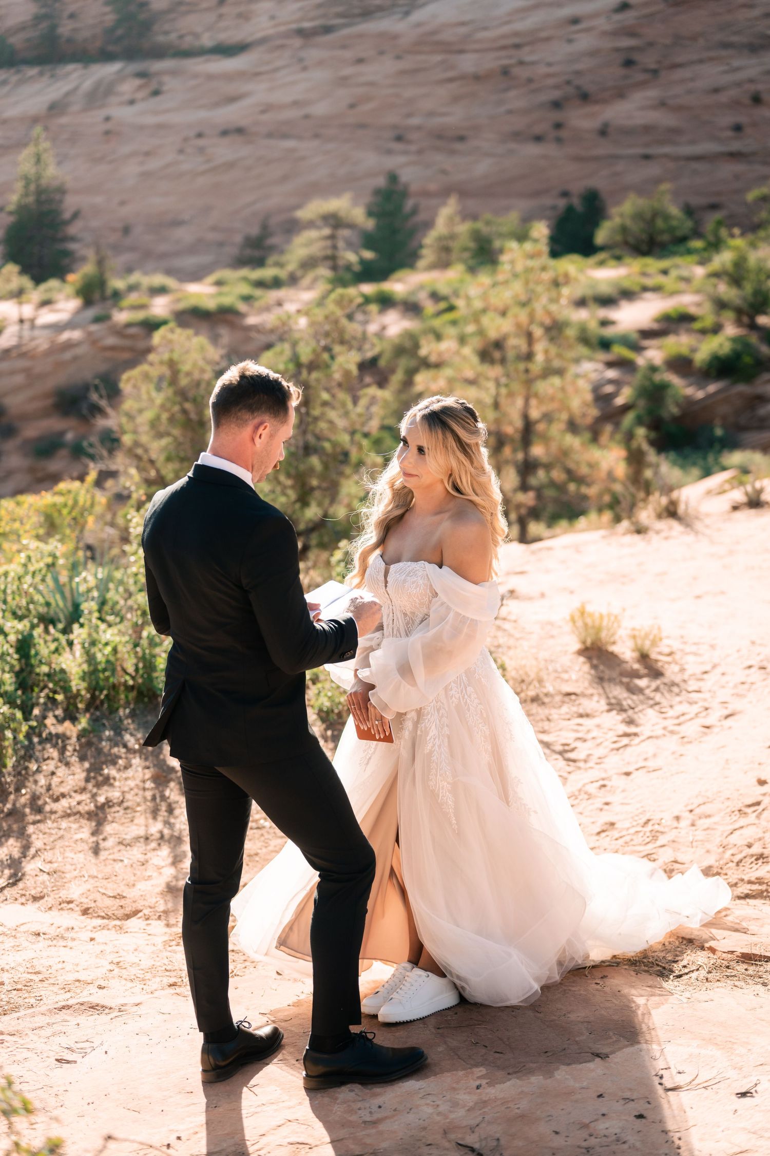 A couple shares an intimate moment during their wedding photoshoot on a desert mountain trail.