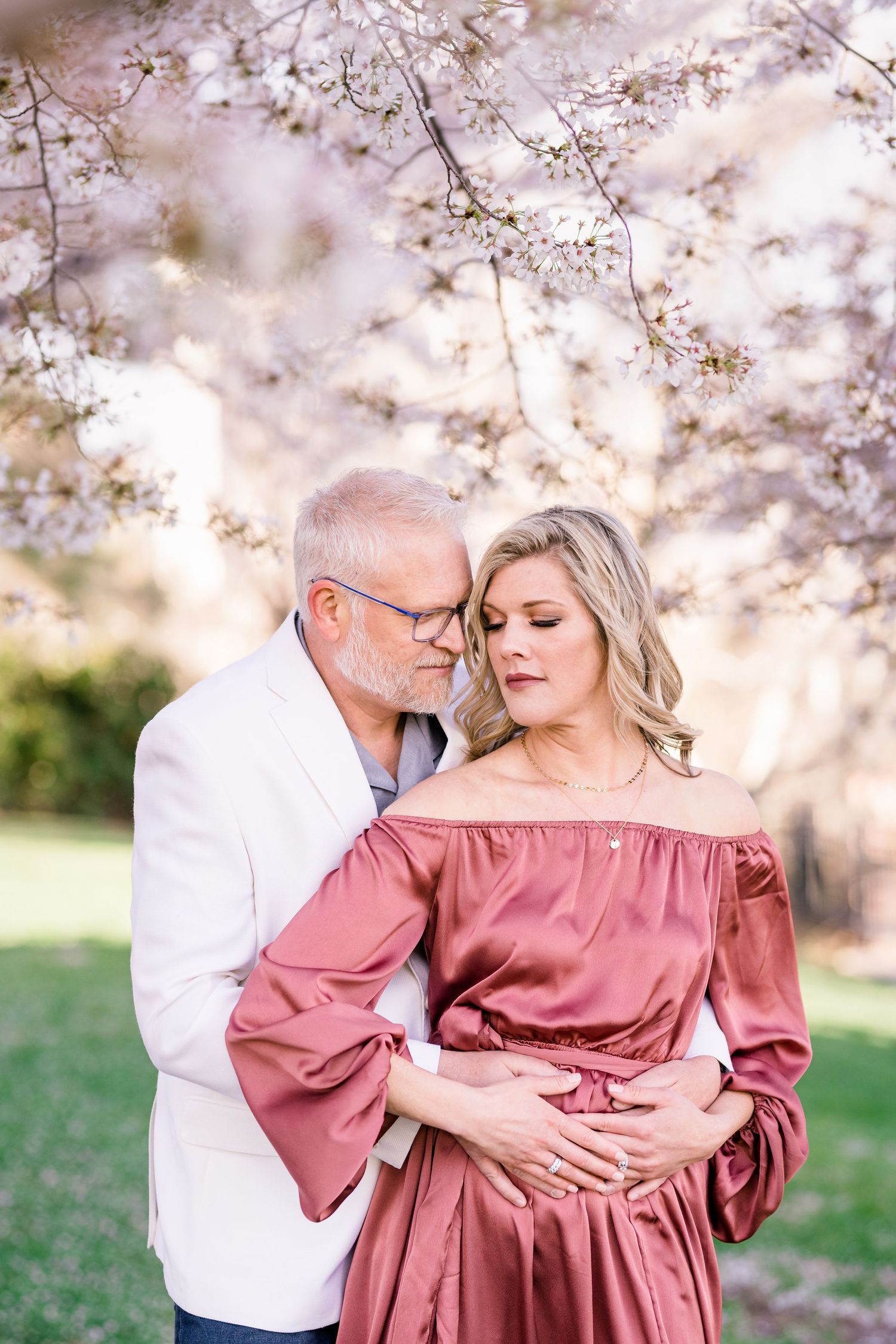 Engaged couple hug warmly at the Capitol cherry blossoms by Utah wedding photographer Coley Cook