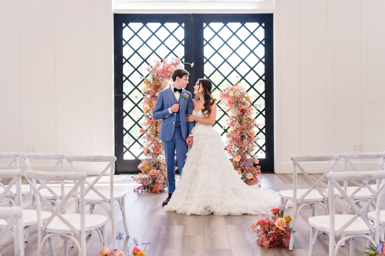 Elegant wedding ceremony setup with black lattice window backdrop and pink florals at River Bridge, a Utah County wedding venue.