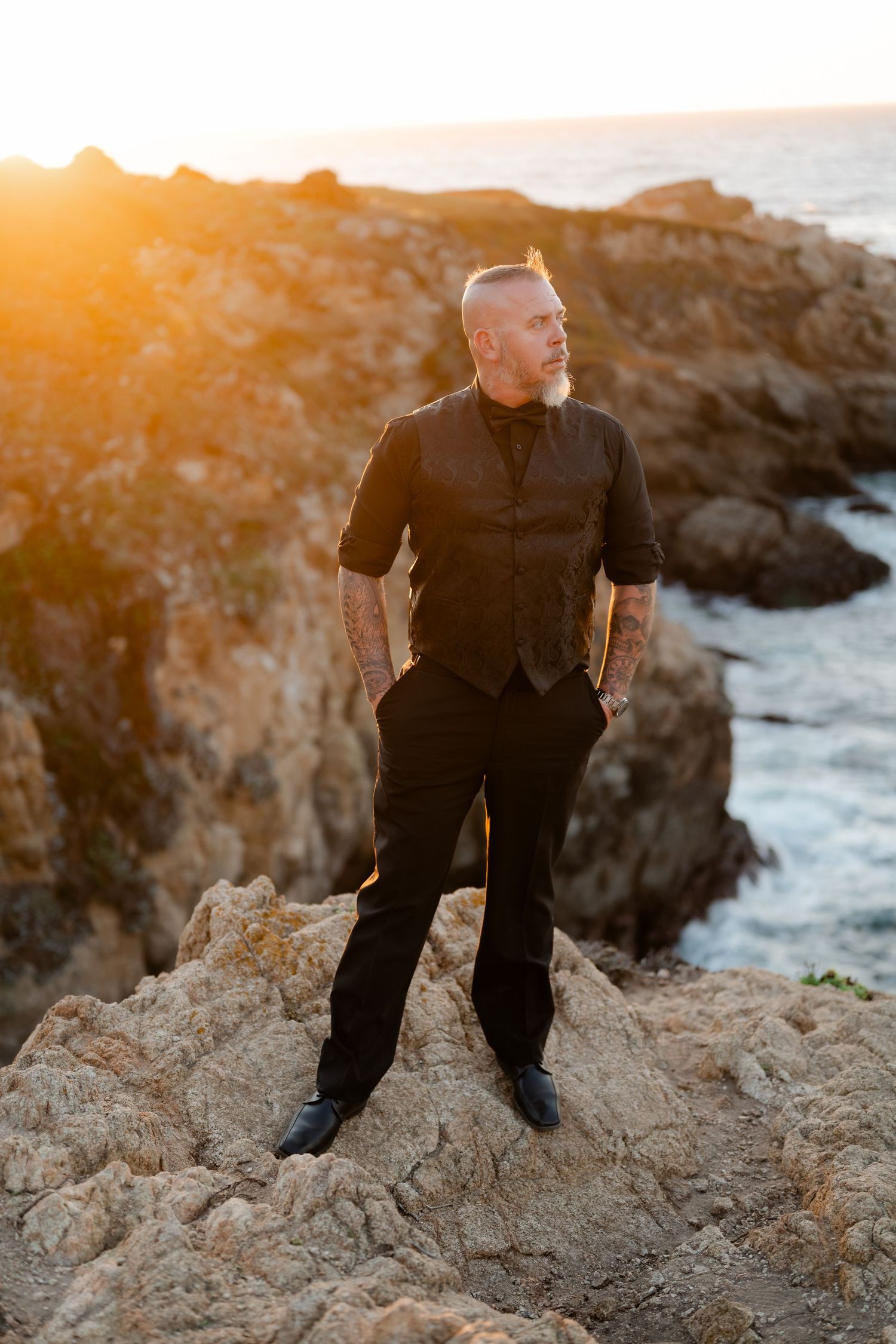 Wedding photography session on dramatic coastal rocks with golden sunset lighting.