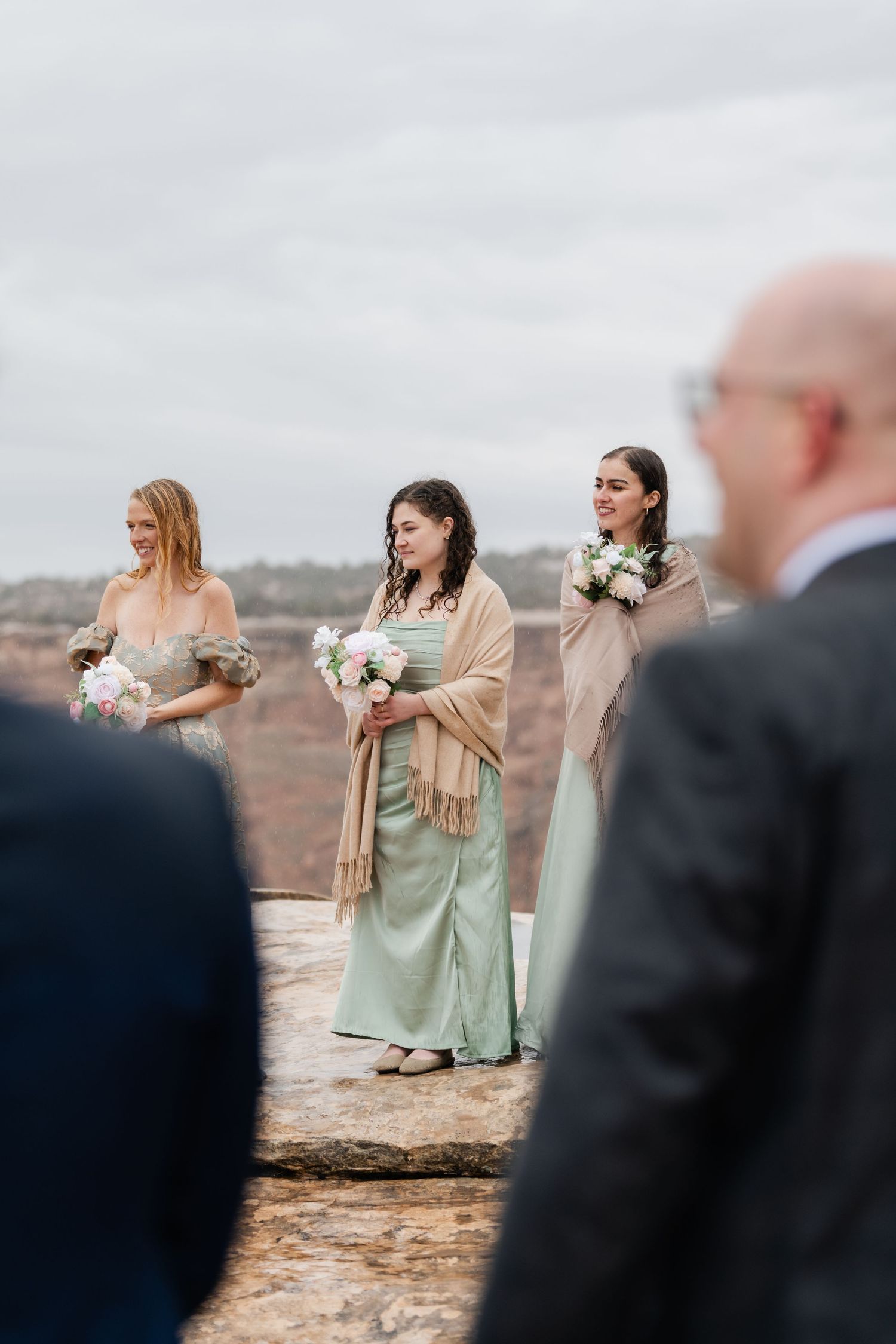 Wedding guests watching ceremony against dramatic desert canyon backdrop.
