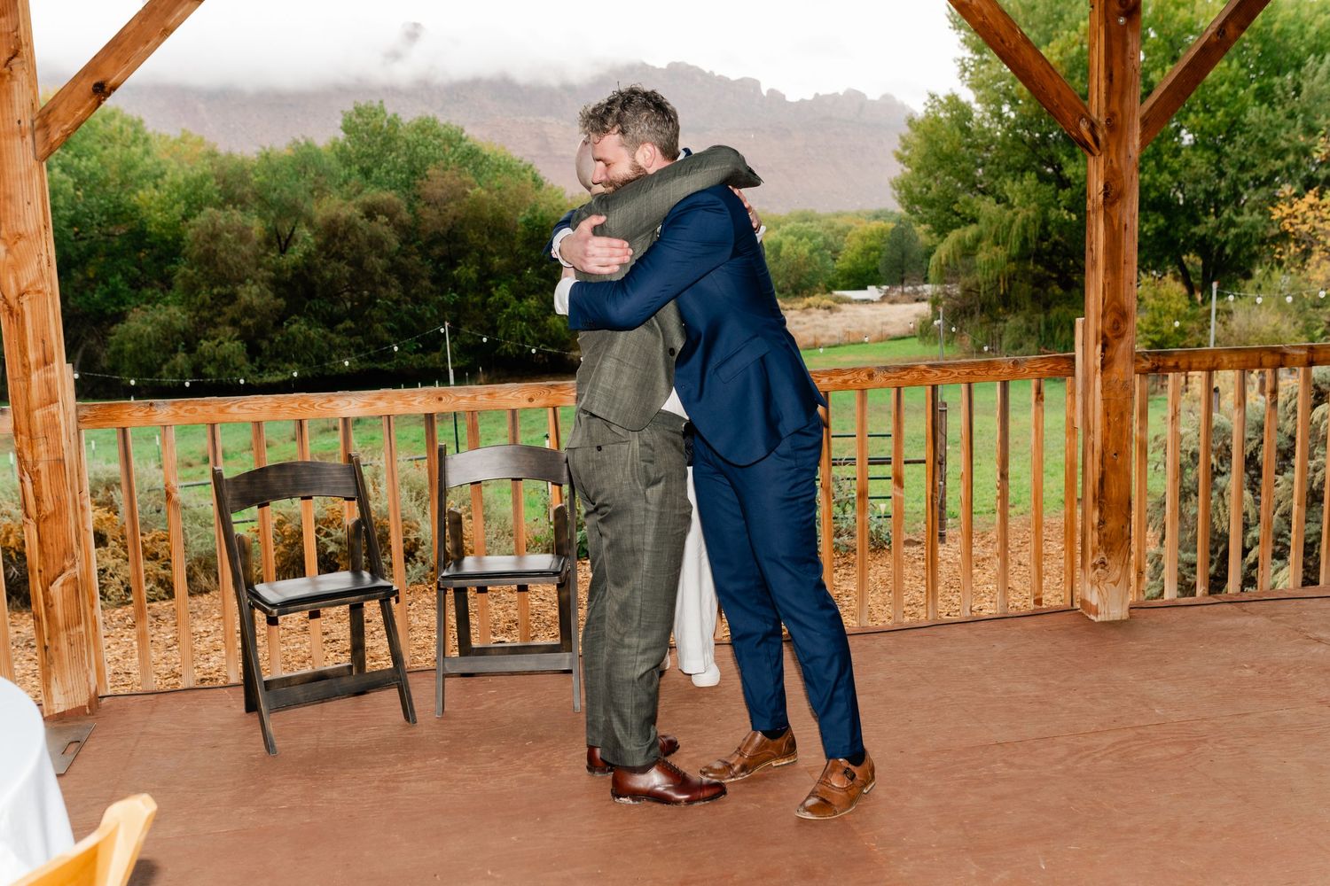 People socializing on a covered patio with scenic mountain views in the background.