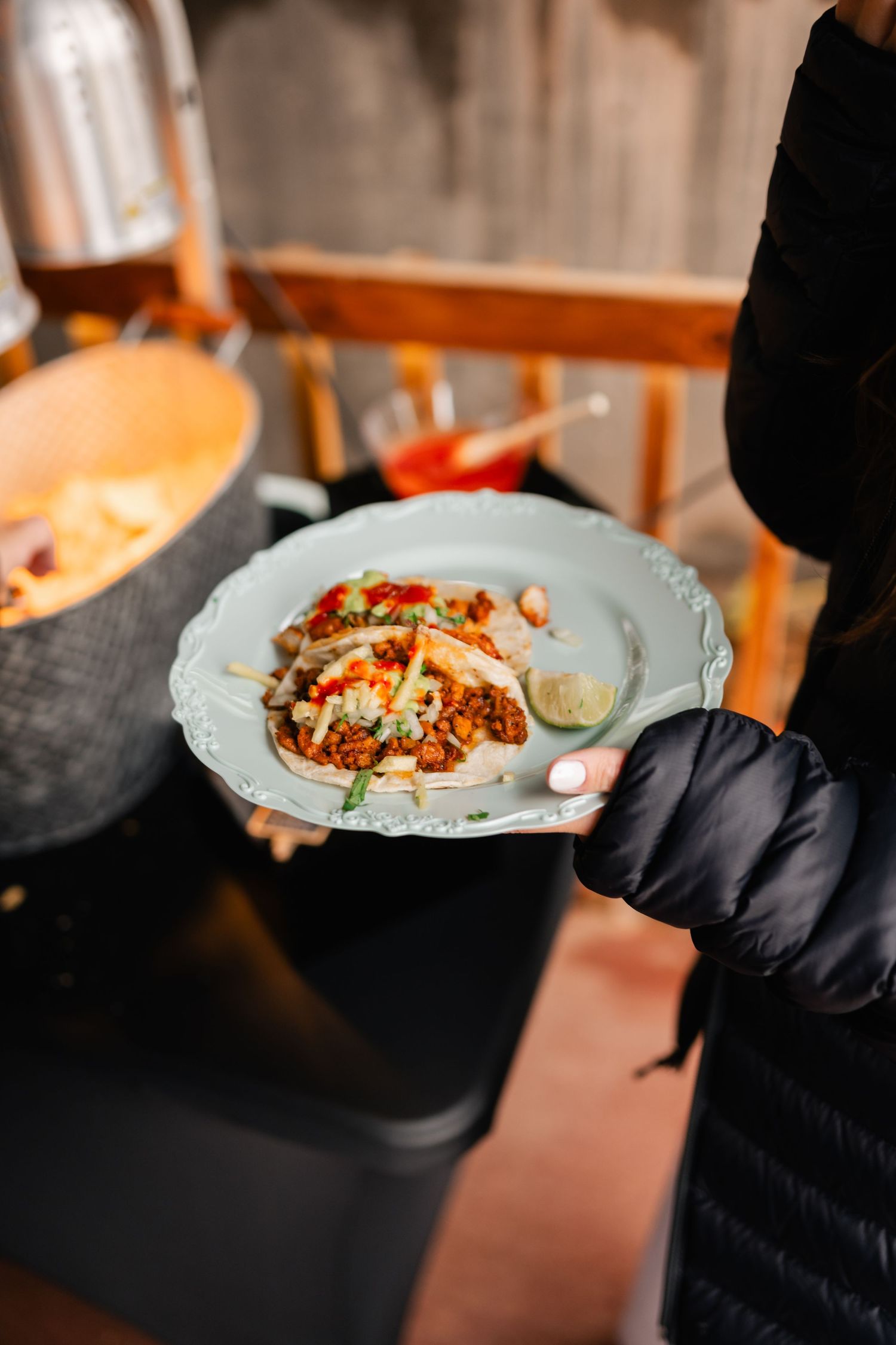 Hands in black gloves serve elegantly plated dishes at an upscale dining event.