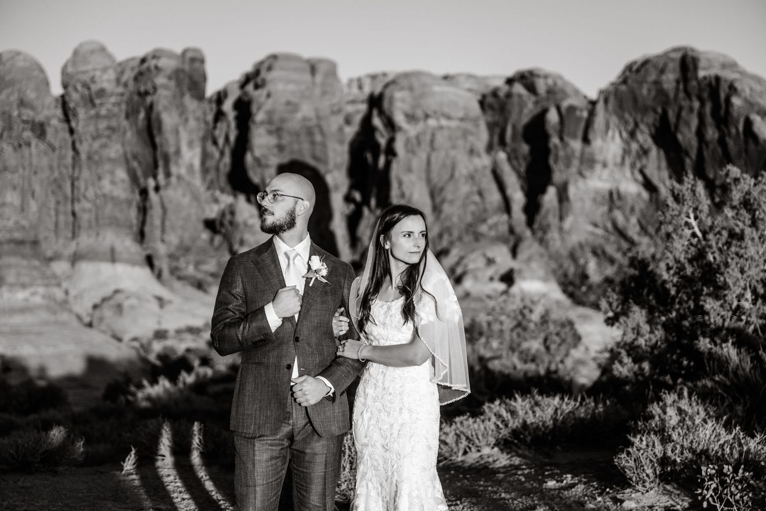 Black and white portrait of newlyweds with desert rock formations in background.