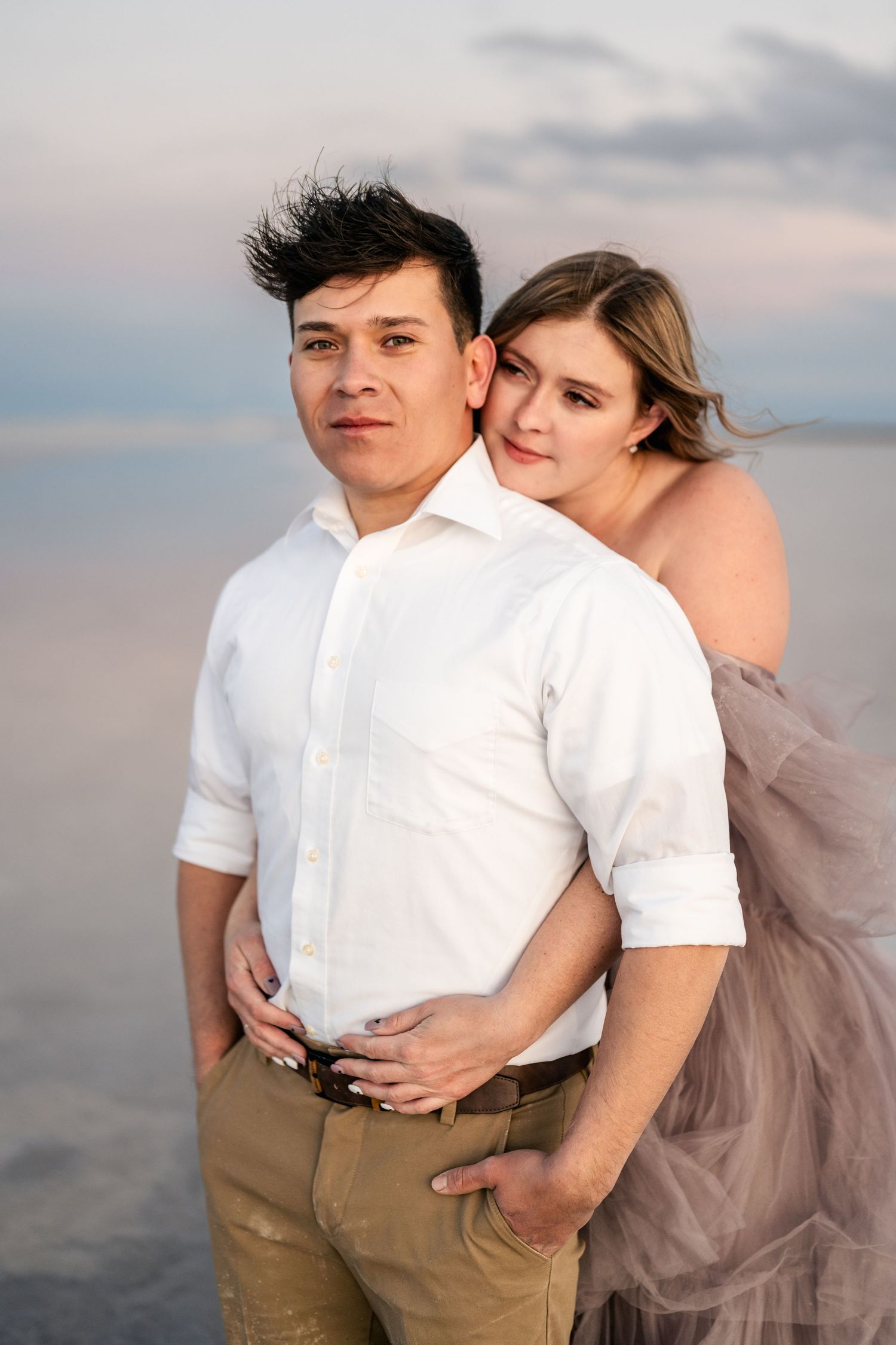 Utah Salt Flats Photographer. Intimate portrait of couple embracing on salt flats during sunset with soft lighting.