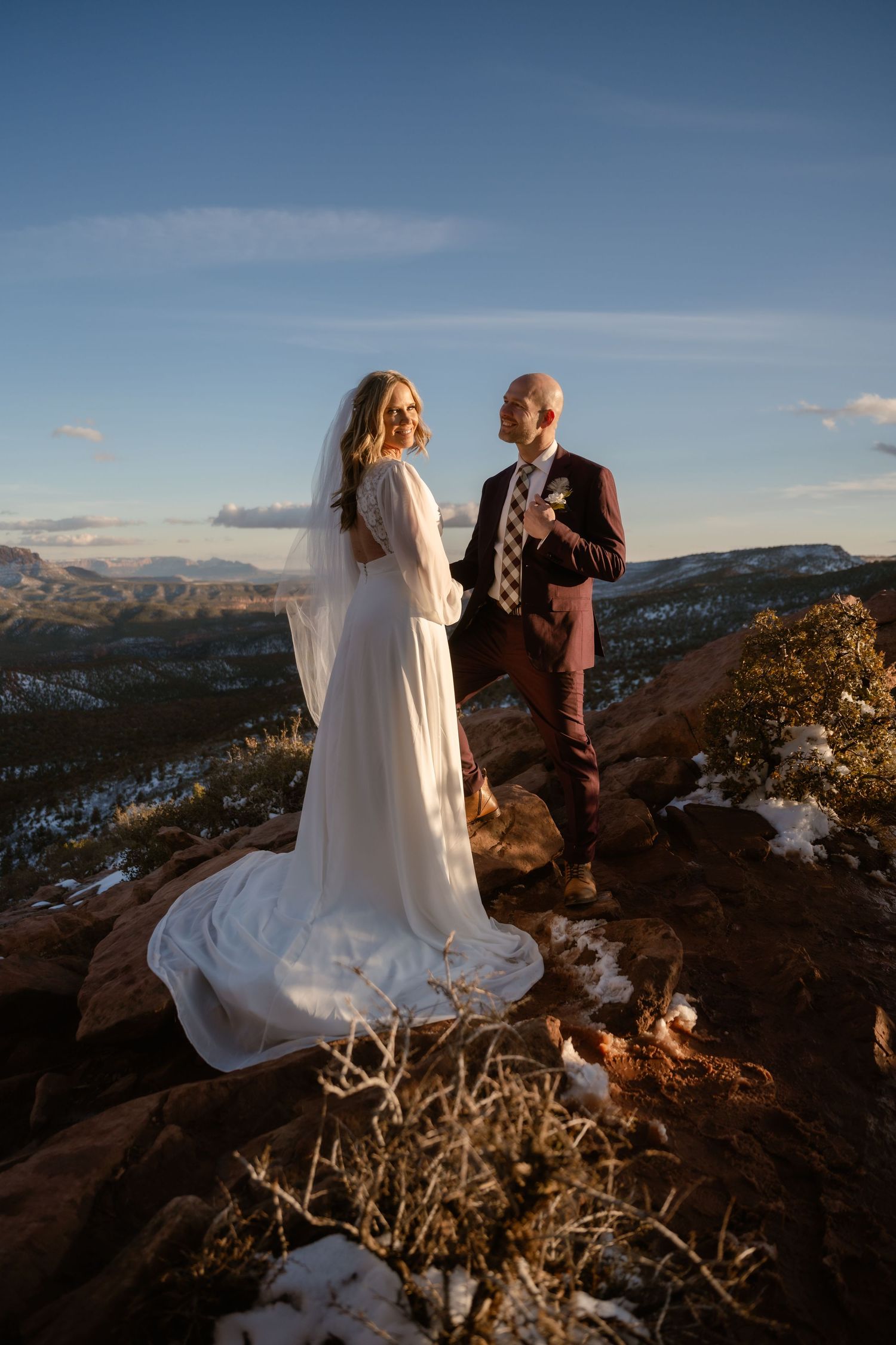 A couple shares an intimate moment during their mountain elopement at sunset with snow-capped peaks in the background.