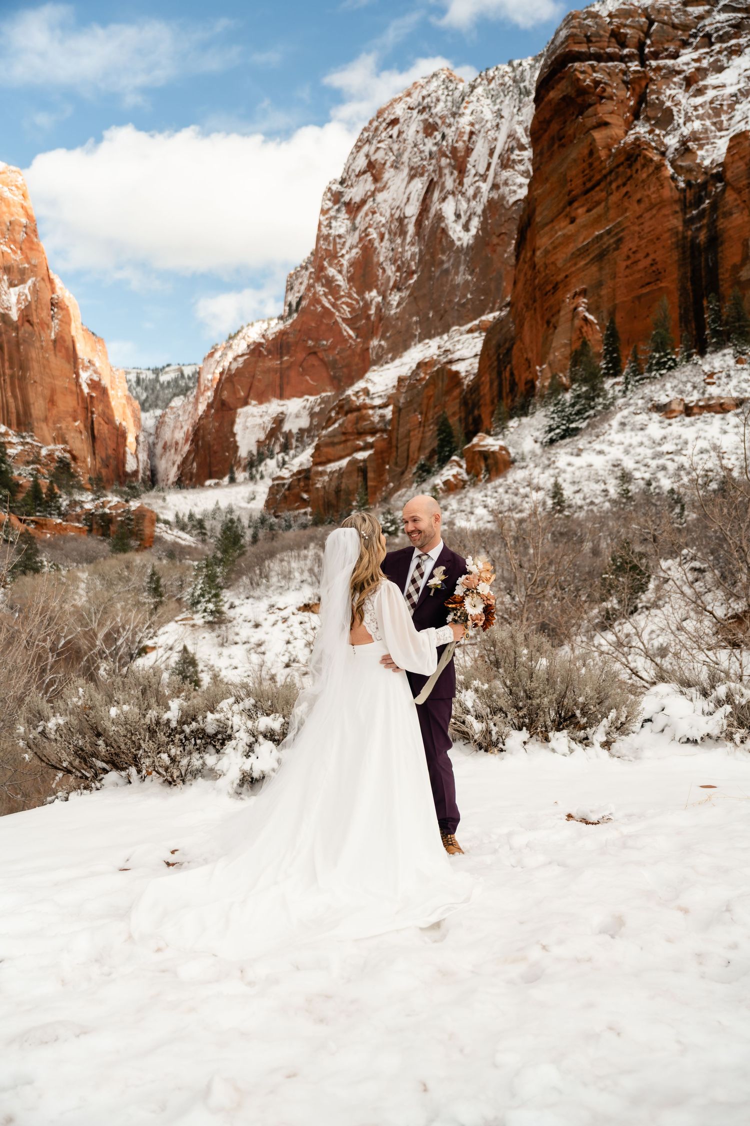 Winter wedding ceremony with snow-covered red cliffs providing a dramatic backdrop.