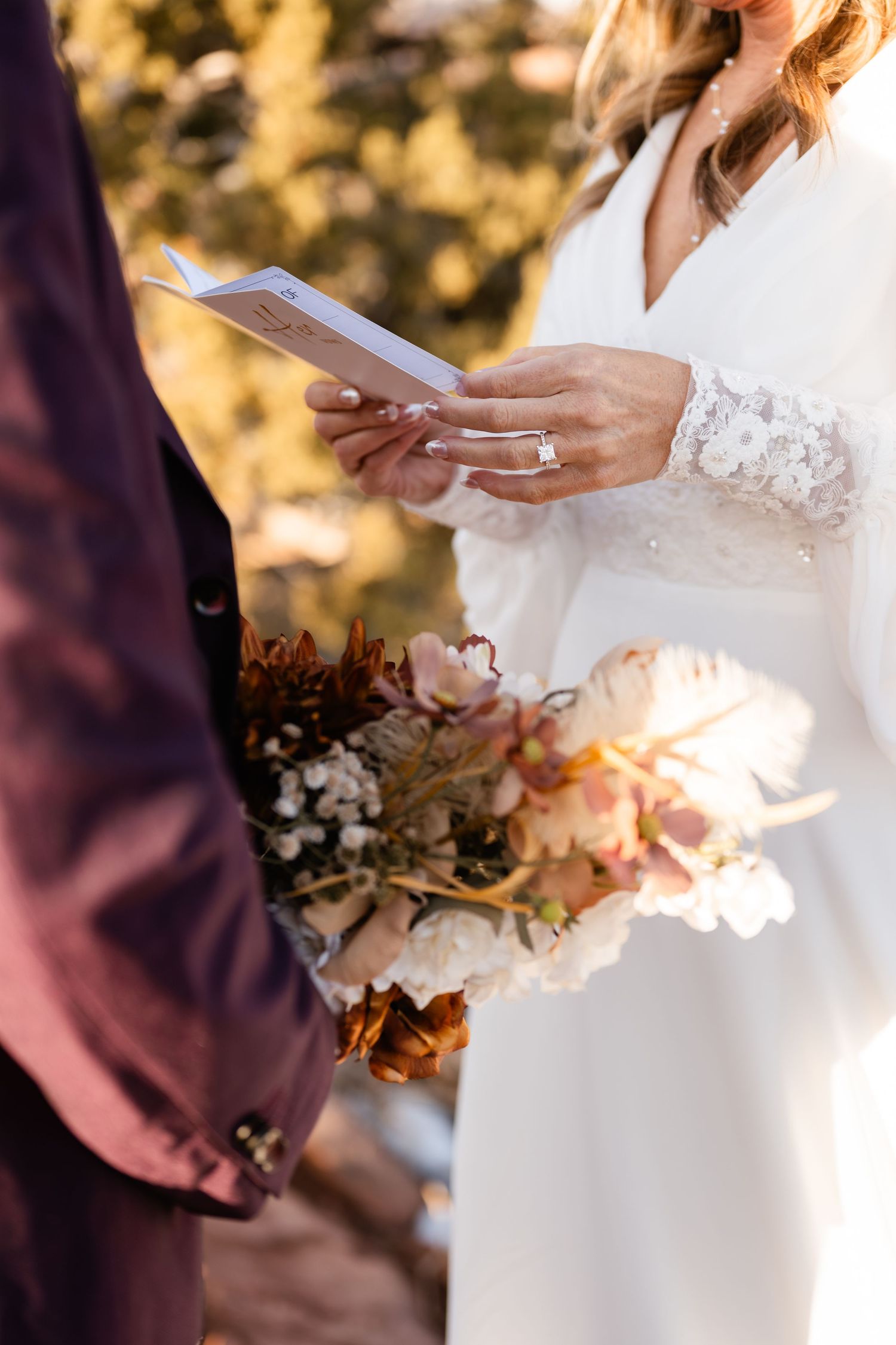 Close-up of hands holding papers during an outdoor wedding ceremony.