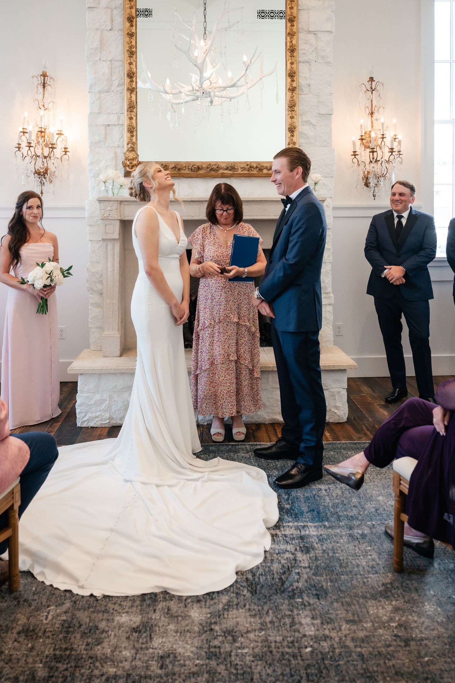 Wedding celebration candid moments in a bright room with ornate gold-framed mirrors.