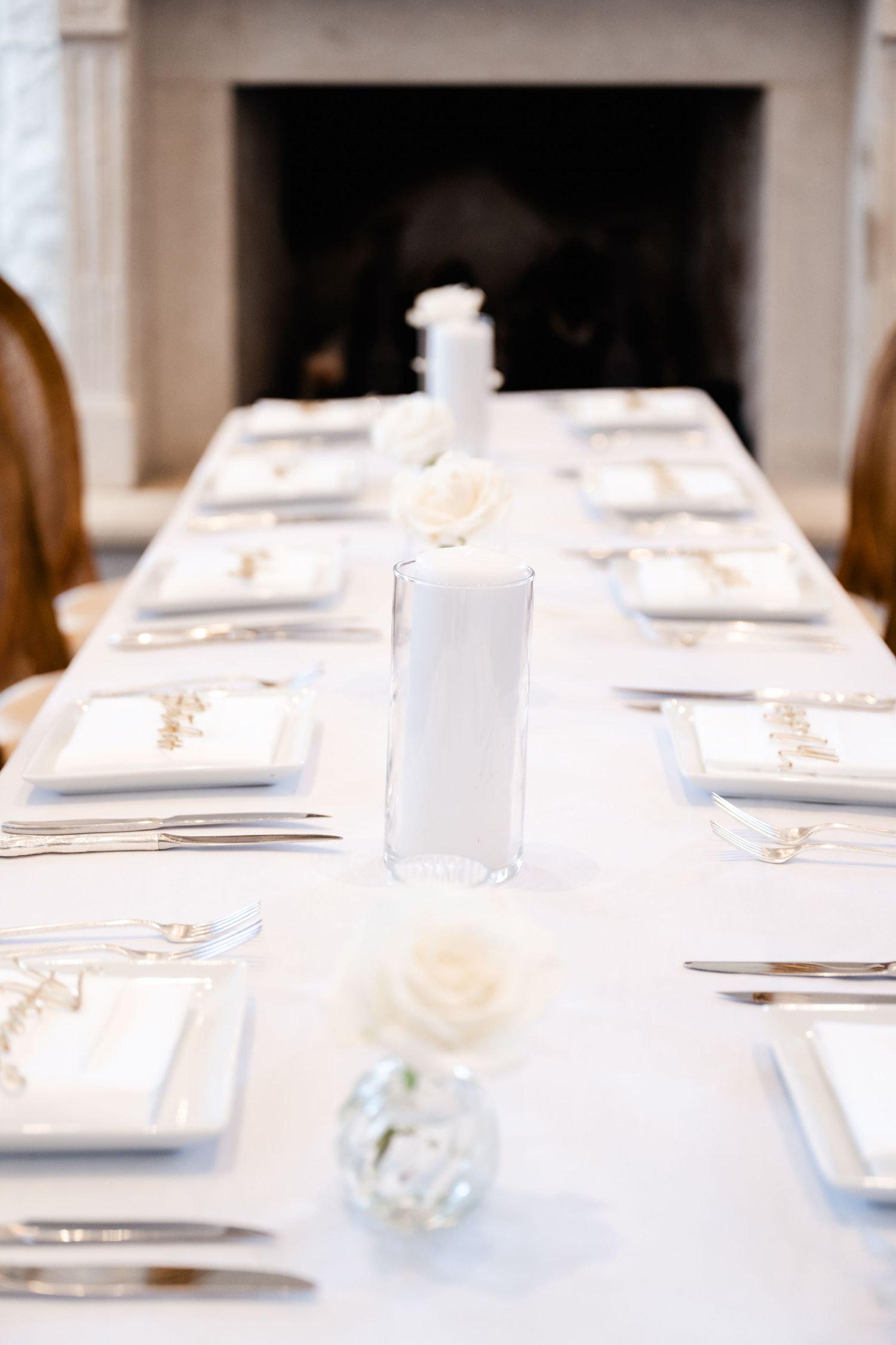 Elegant white table settings with place cards arranged for a formal wedding reception.