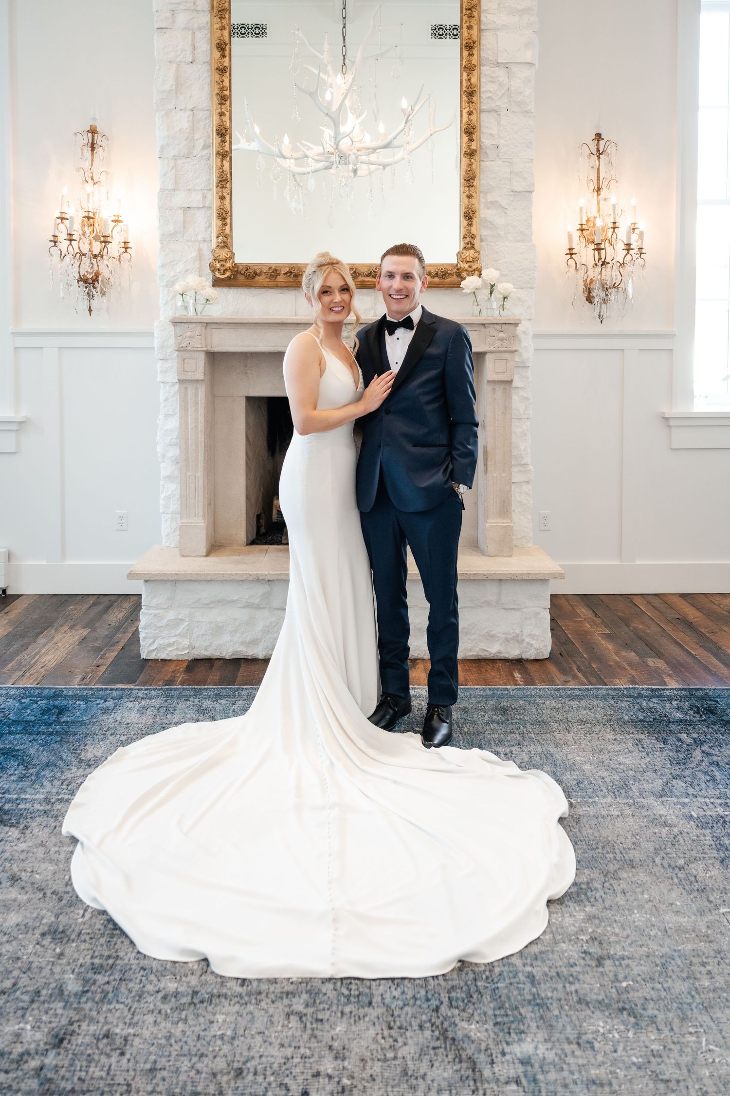 A couple dancing in an elegant white room with chandeliers and ornate gold-framed mirrors.