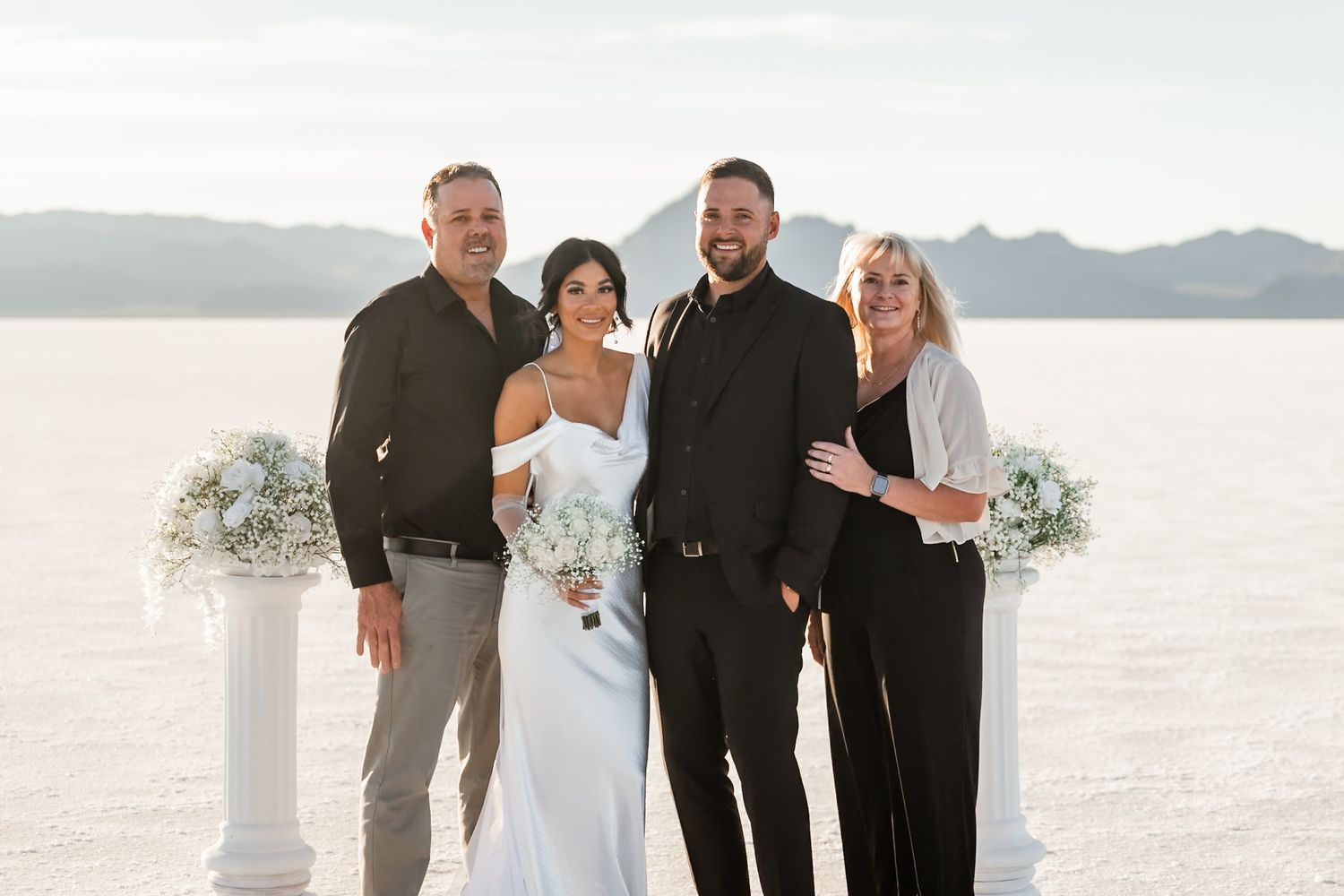 Wedding party poses together on the stunning Bonneville Salt Flats with mountains in background.