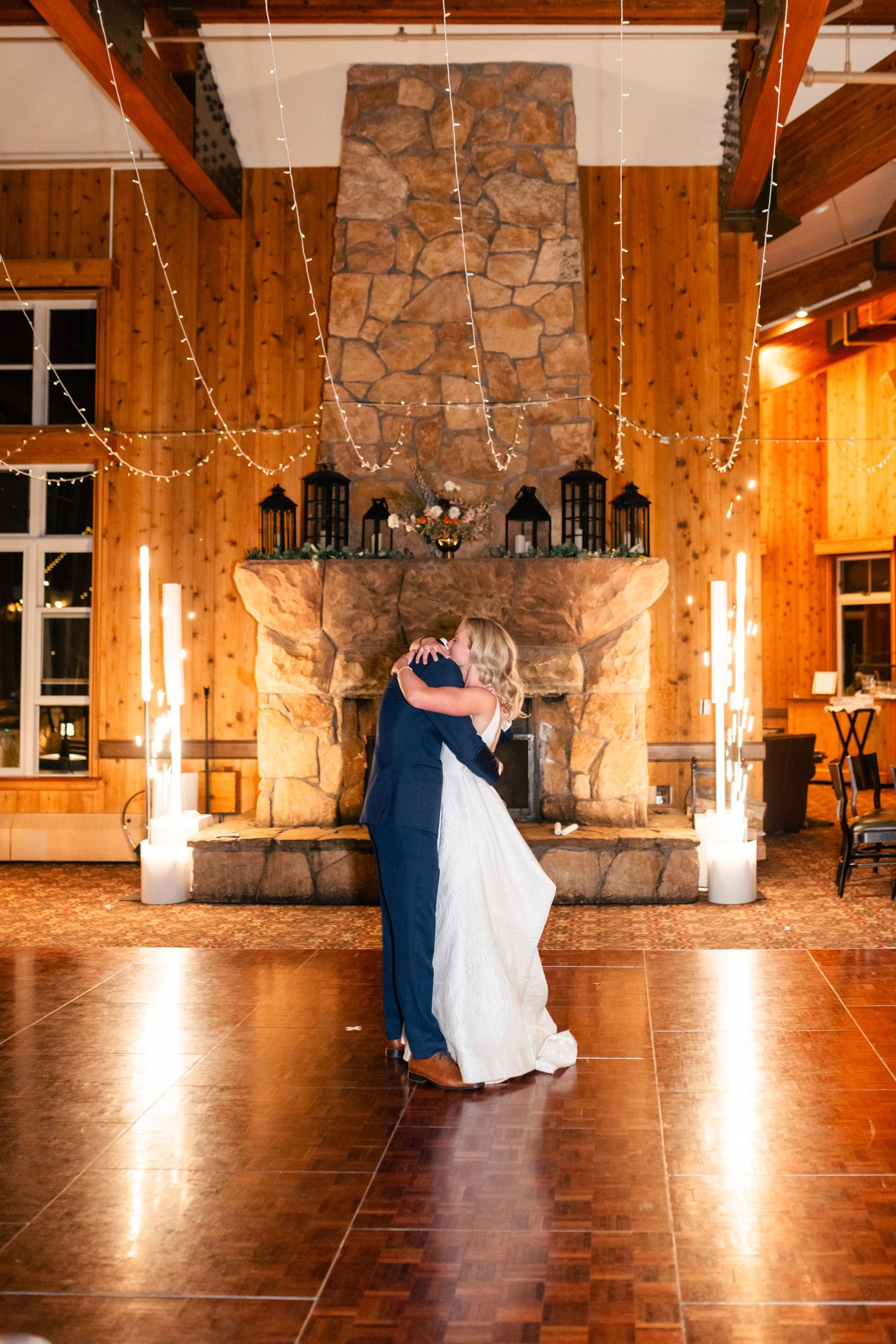A romantic first dance in a rustic lodge venue with stone walls and warm lighting.