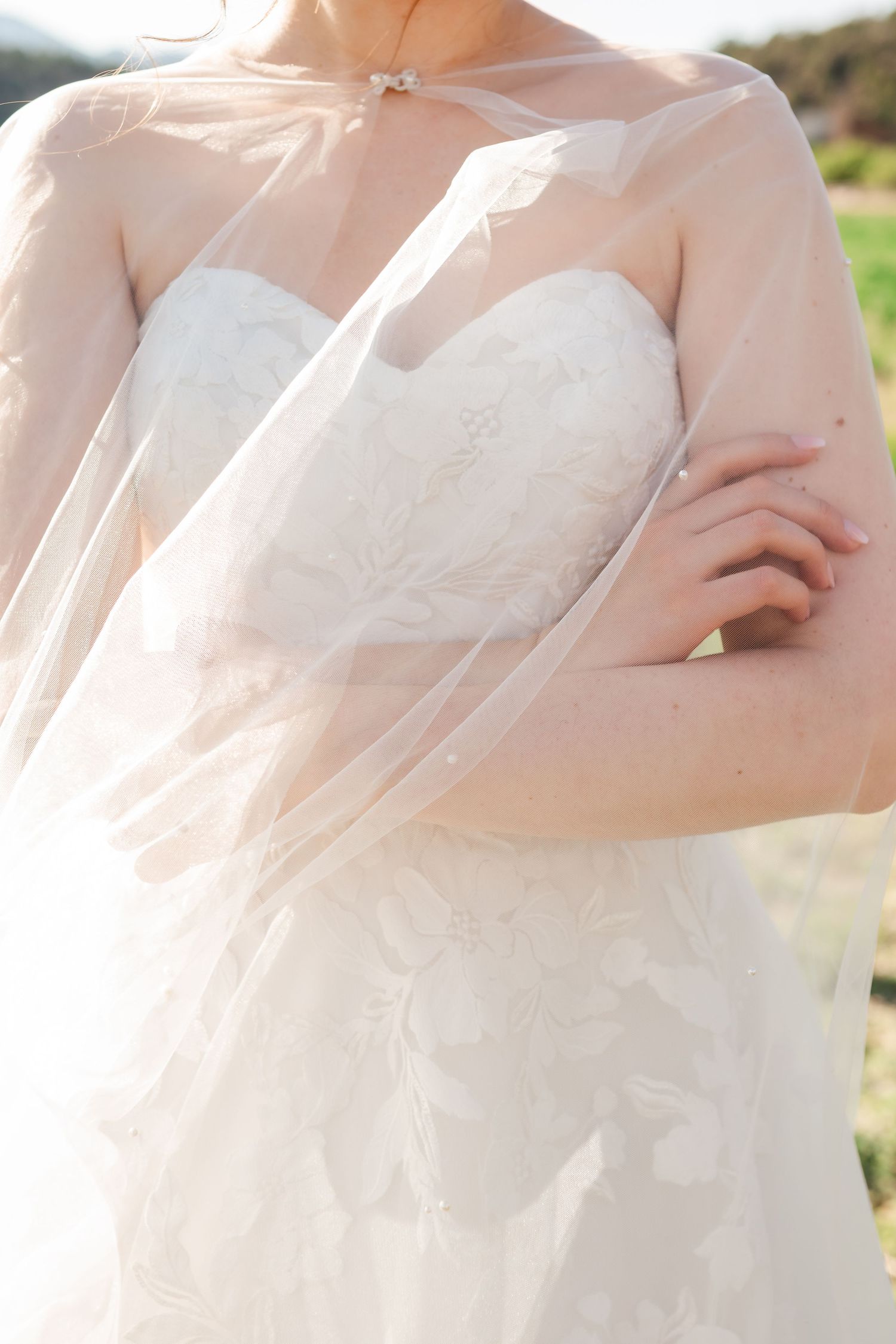 Close-up details of delicate white wedding dress fabric in natural sunlight.