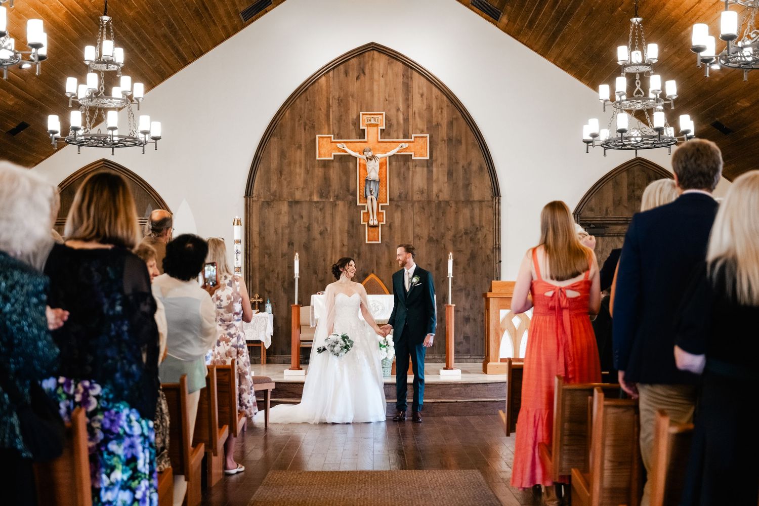 Interior of a church sanctuary with wooden beams and stained glass during a wedding ceremony.