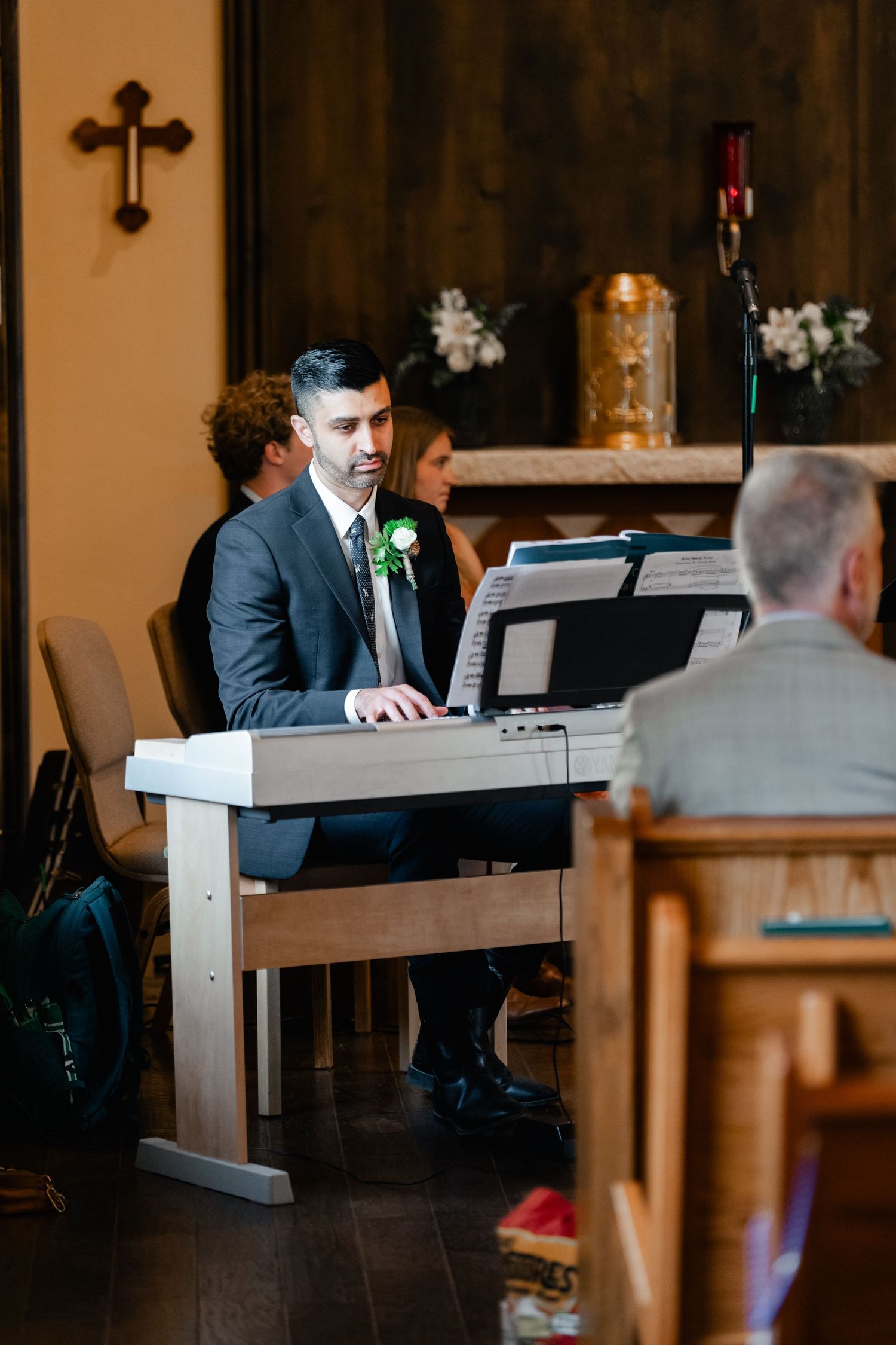 Musicians playing keyboard instruments during a wedding ceremony in a dimly lit church setting.