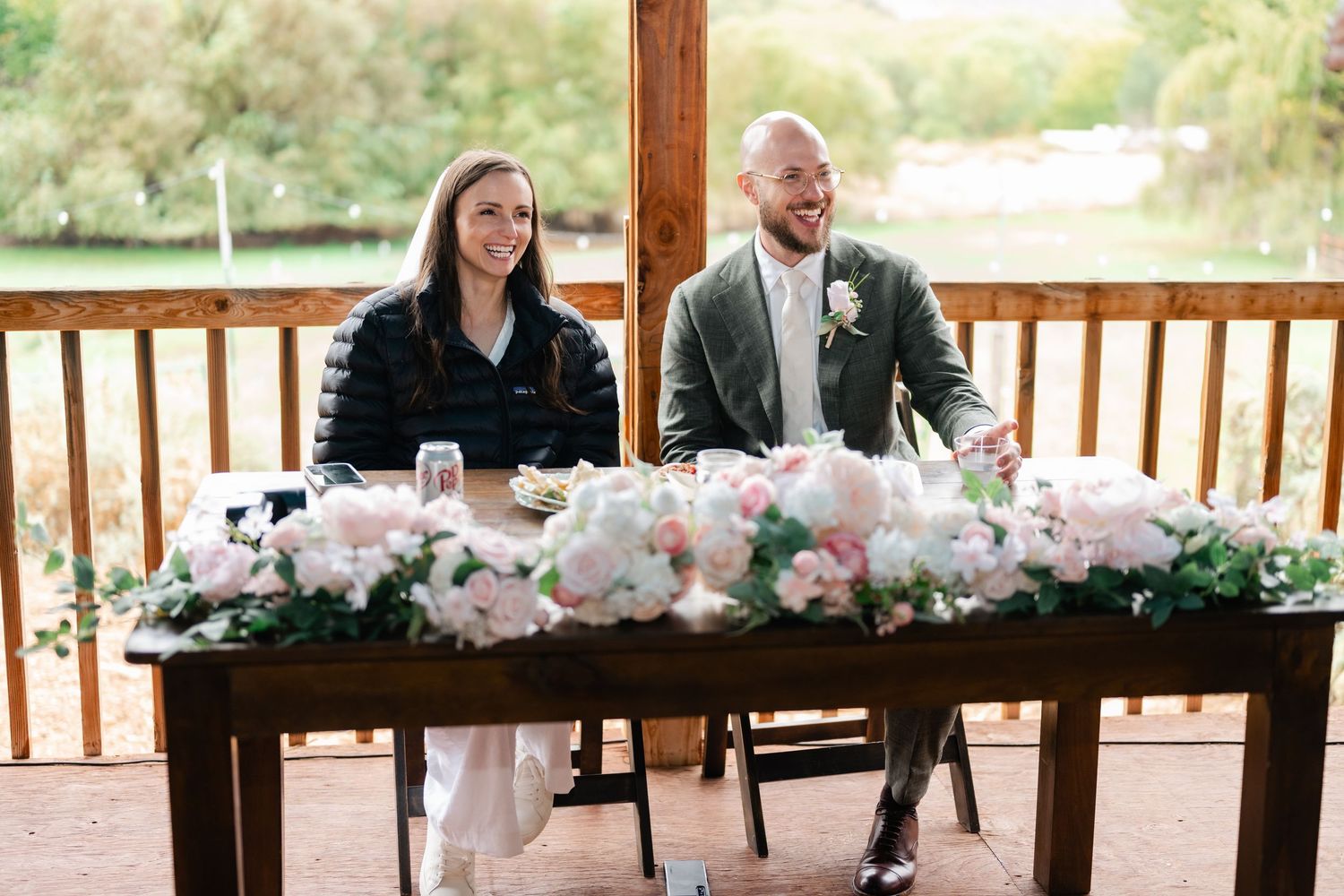 Floral arrangements decorate rustic wooden pavilion during daytime celebration.