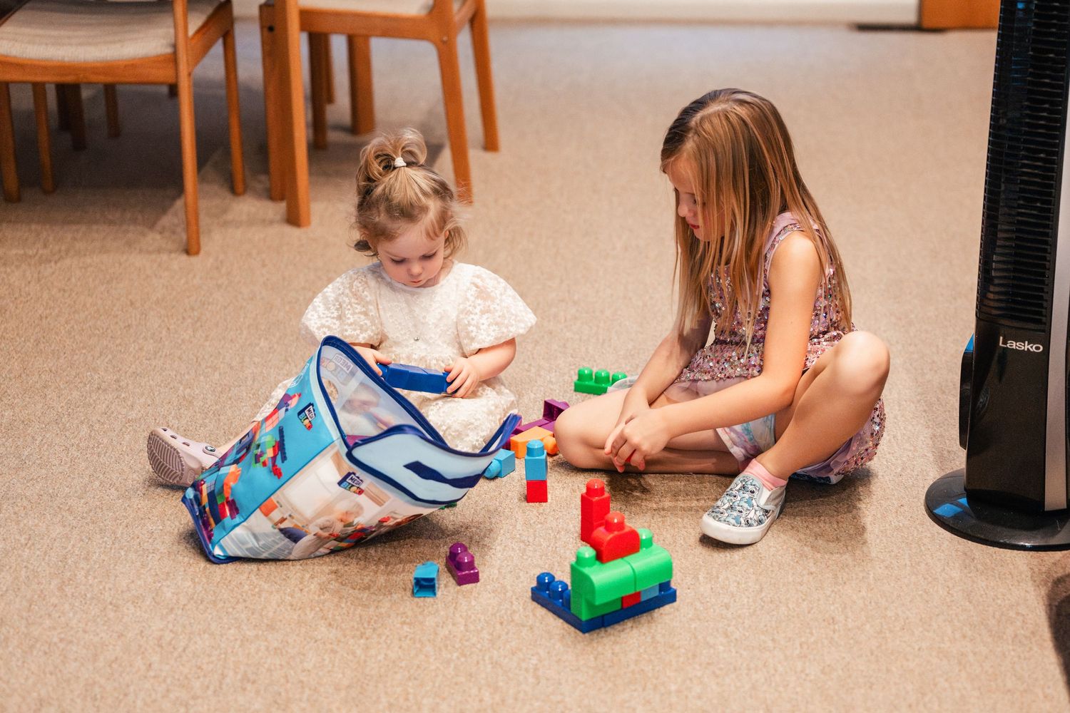 Children playing with toys on a beige carpeted floor.