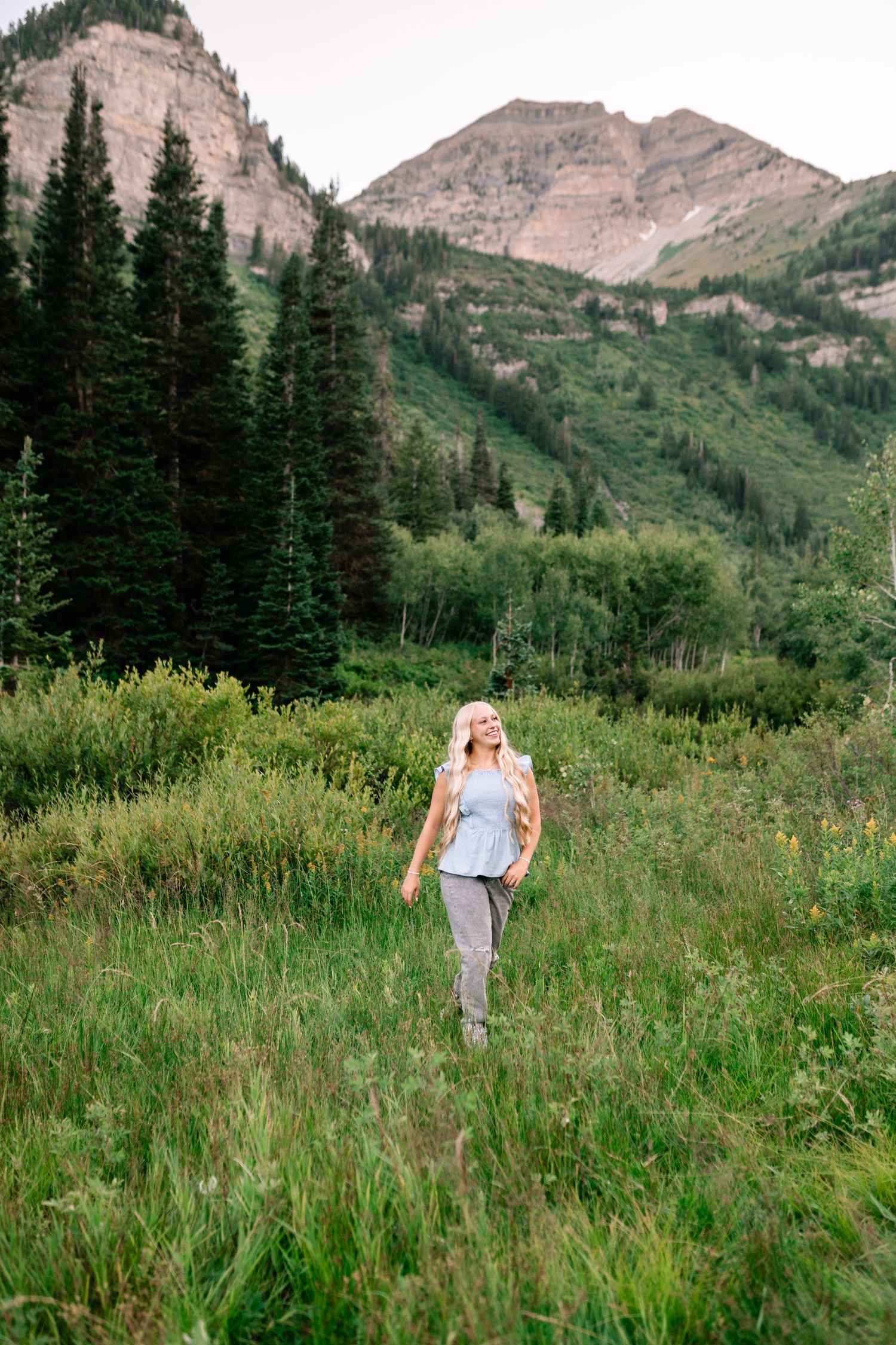 senior girl walking through a mountain meadow during her summer senior session