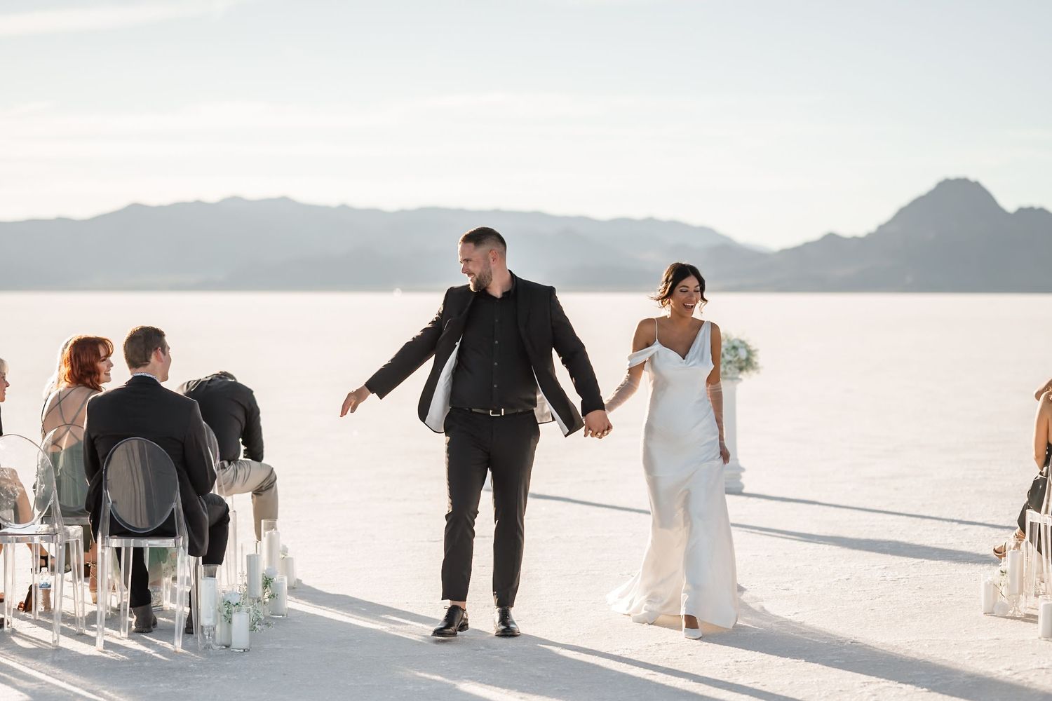 A panoramic view of a wedding ceremony setup on the Bonneville Salt Flats with mountains in the background.