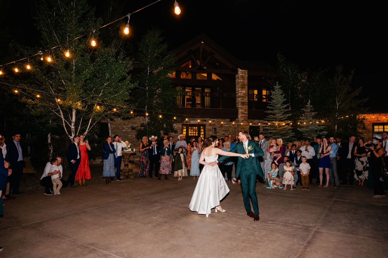 Outdoor wedding reception dance floor with string lights creating a romantic evening atmosphere.