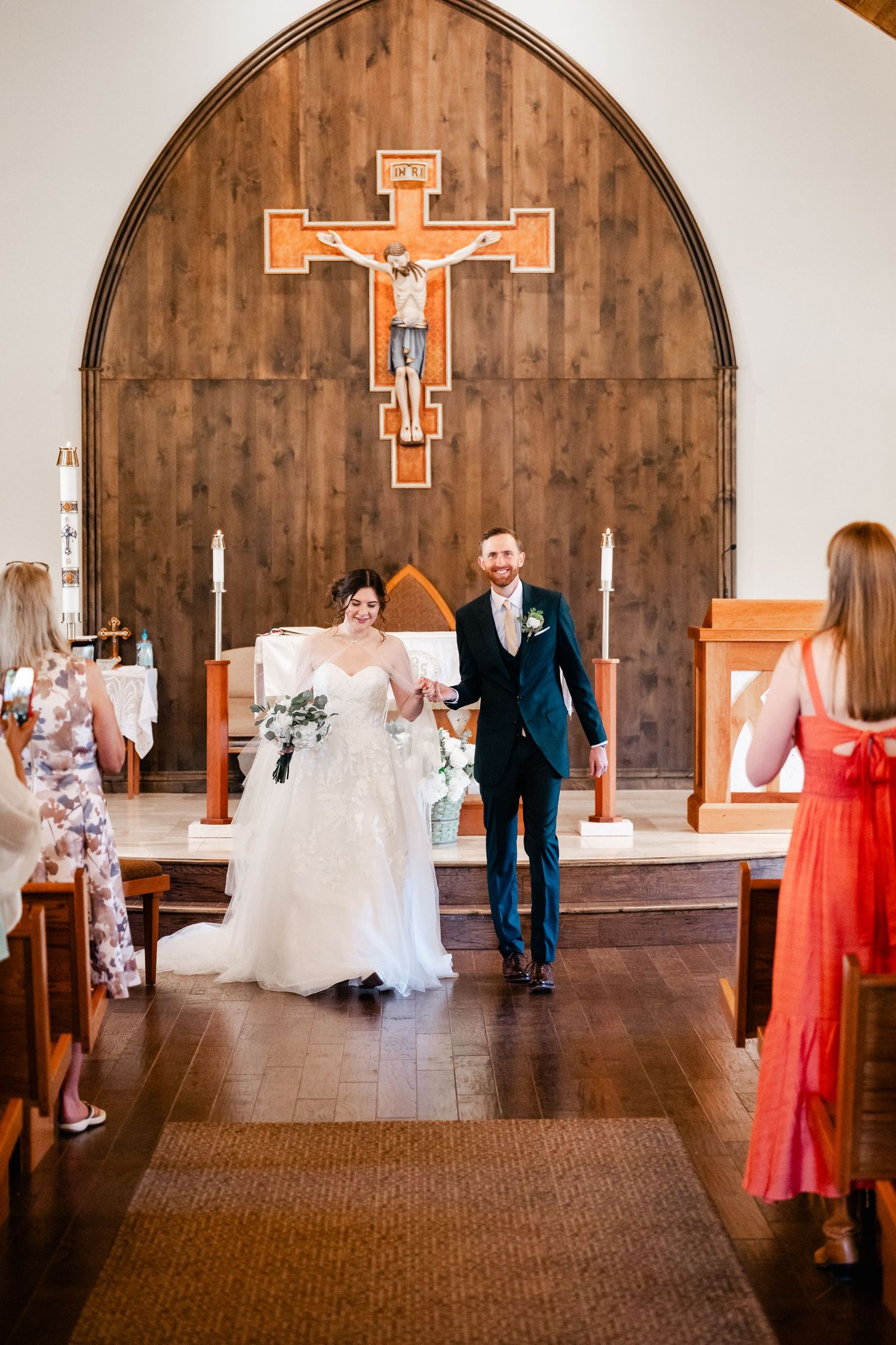 Wedding party members dancing and celebrating in a church sanctuary with wooden walls and decorative crosses.
