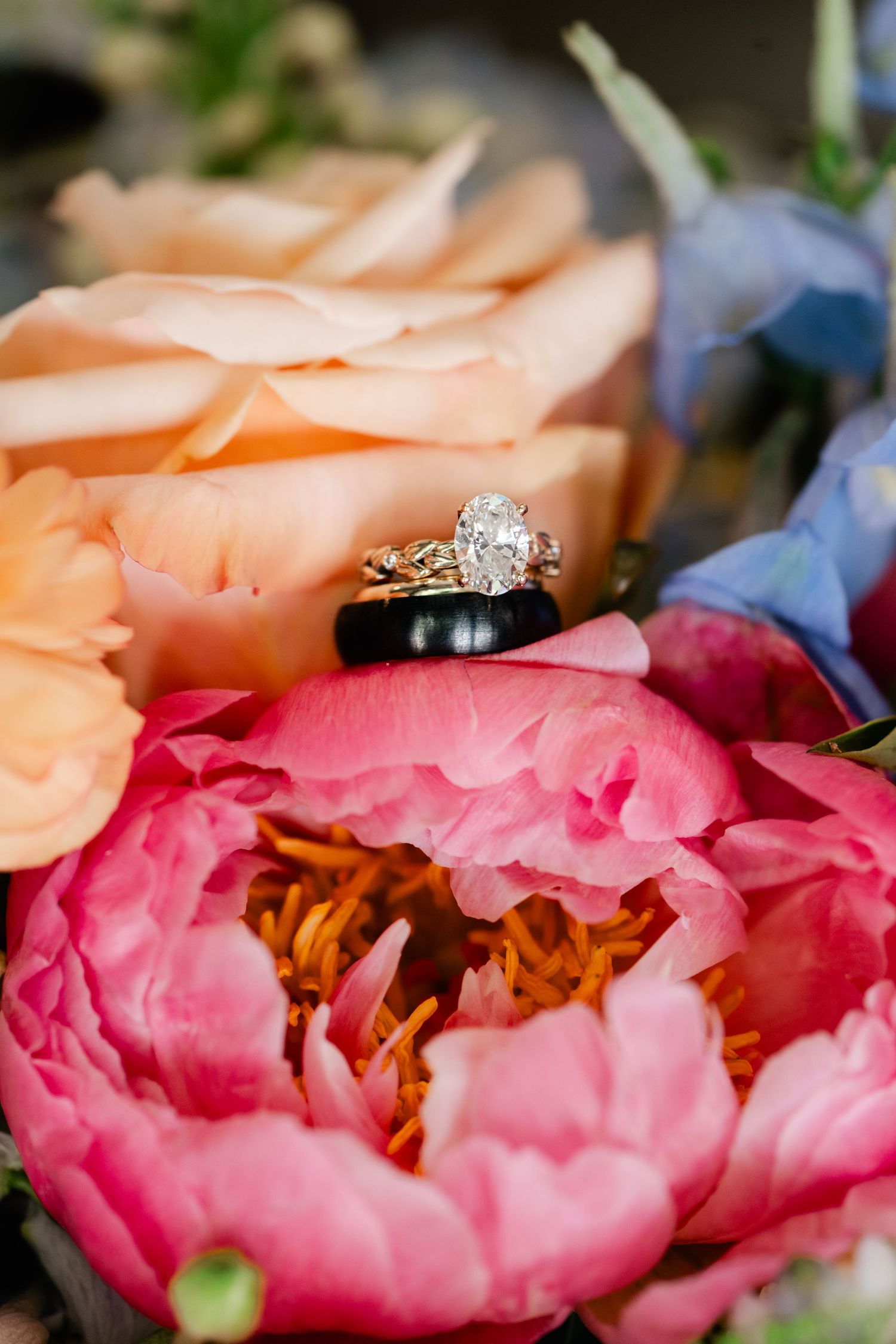 Wedding rings nestled among pink and peach colored peonies in macro photography. Park City Wedding Photographer.