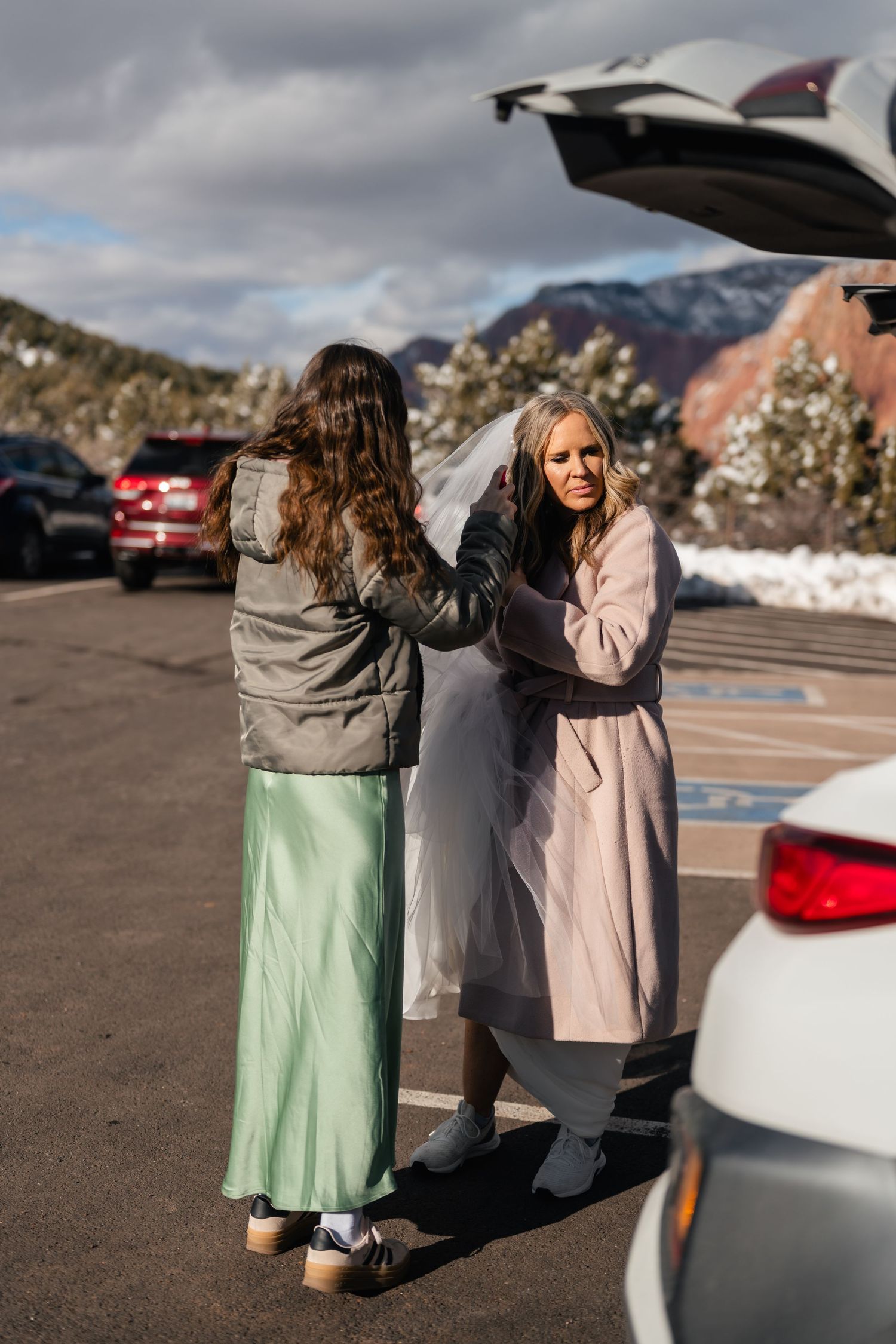 Three people in winter coats standing together in a parking area.