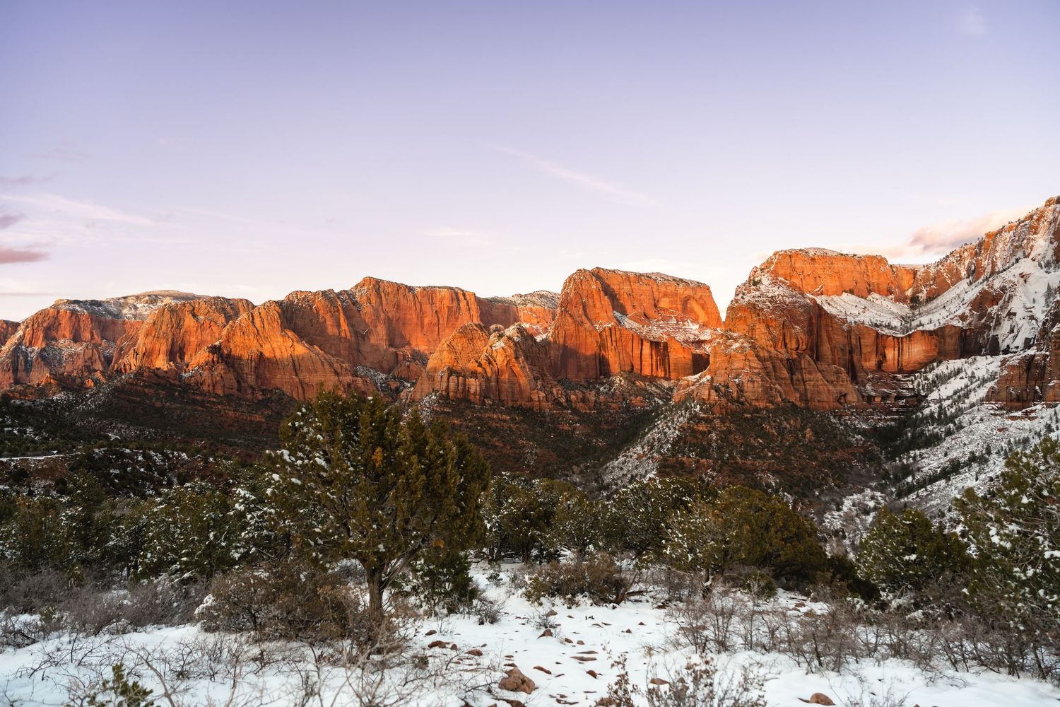 Snow-covered red rock formations at sunset create a stunning backdrop for an outdoor winter wedding.