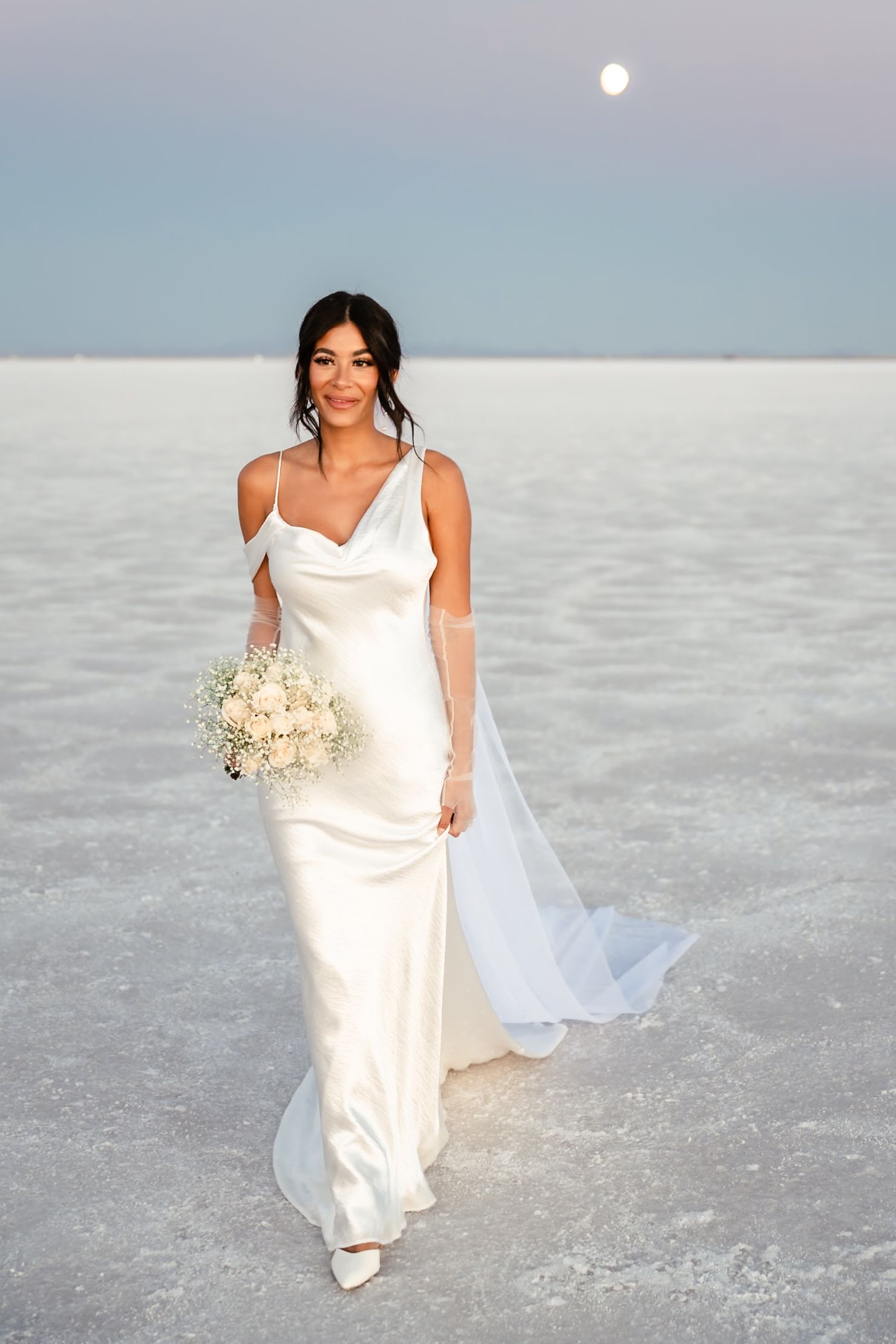 A bride in a flowing white gown walks gracefully across the salt flats.