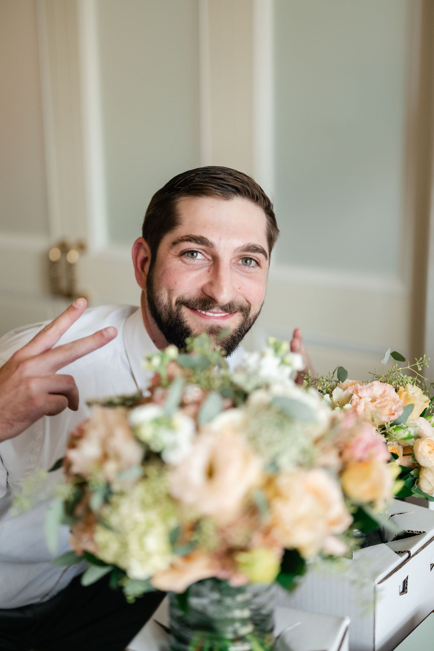 A floral centerpiece arrangement of peach and white blooms sits on a table.