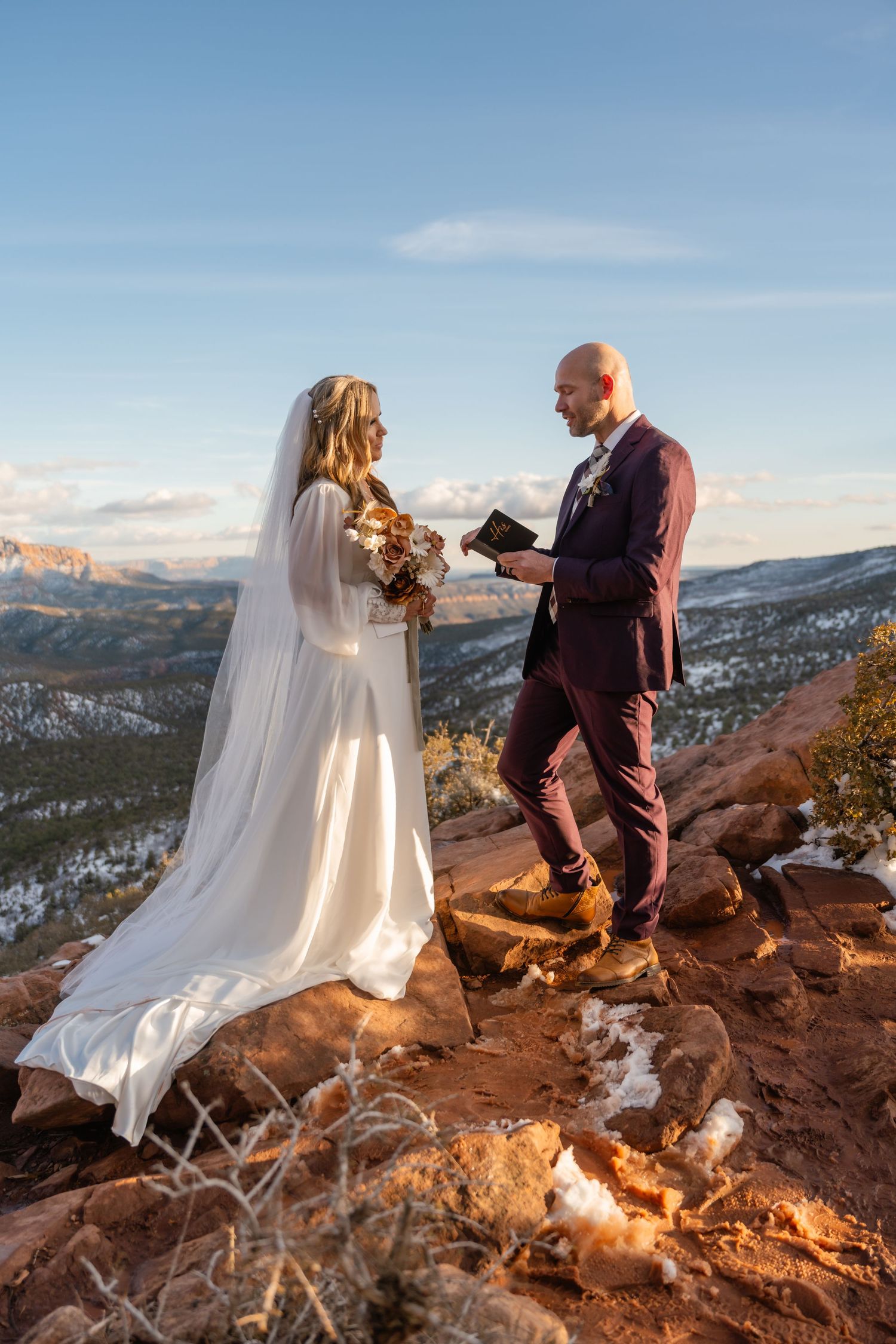 Intimate wedding ceremony on red rocks with sweeping mountain vistas at sunset.