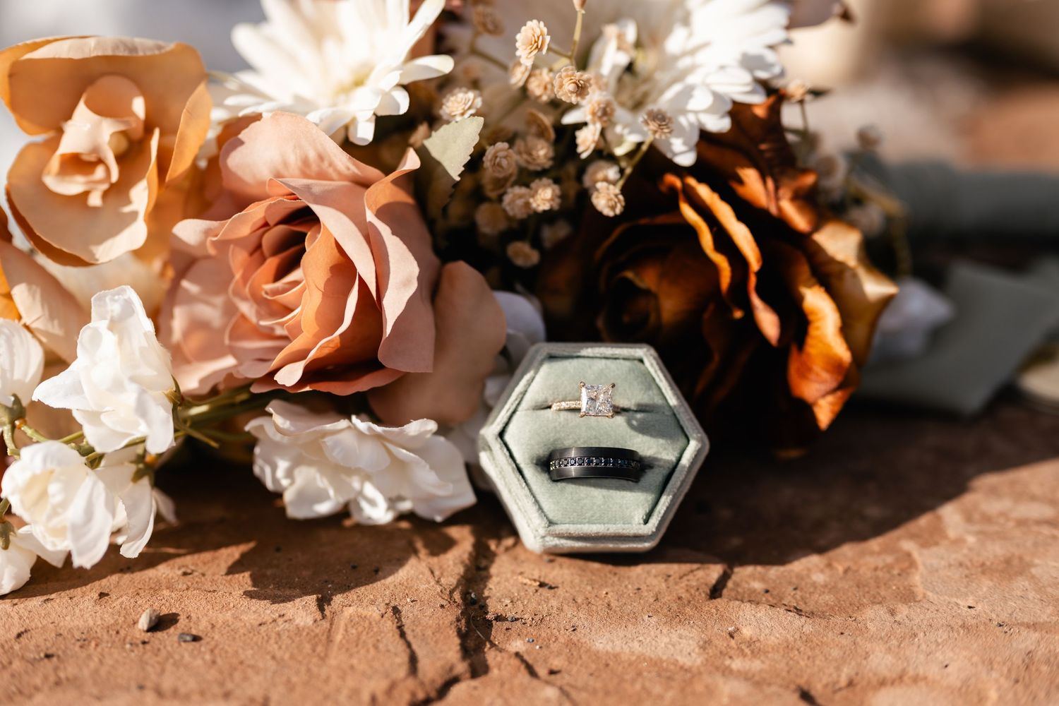 Close-up of delicate white and pink floral arrangements with metallic accents on red stone.
