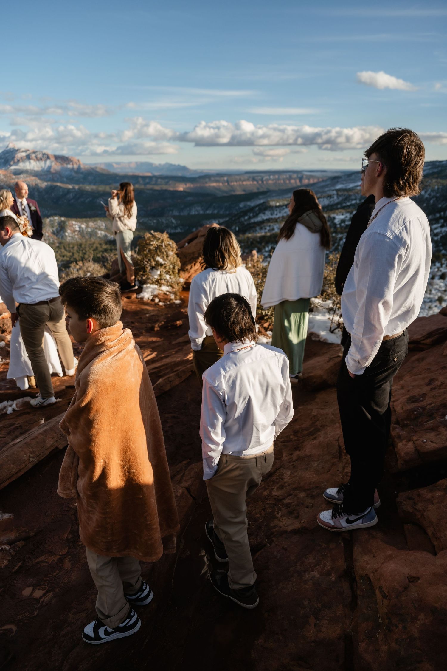 Group gathered at scenic overlook with panoramic views of snow-dusted red rock canyons.