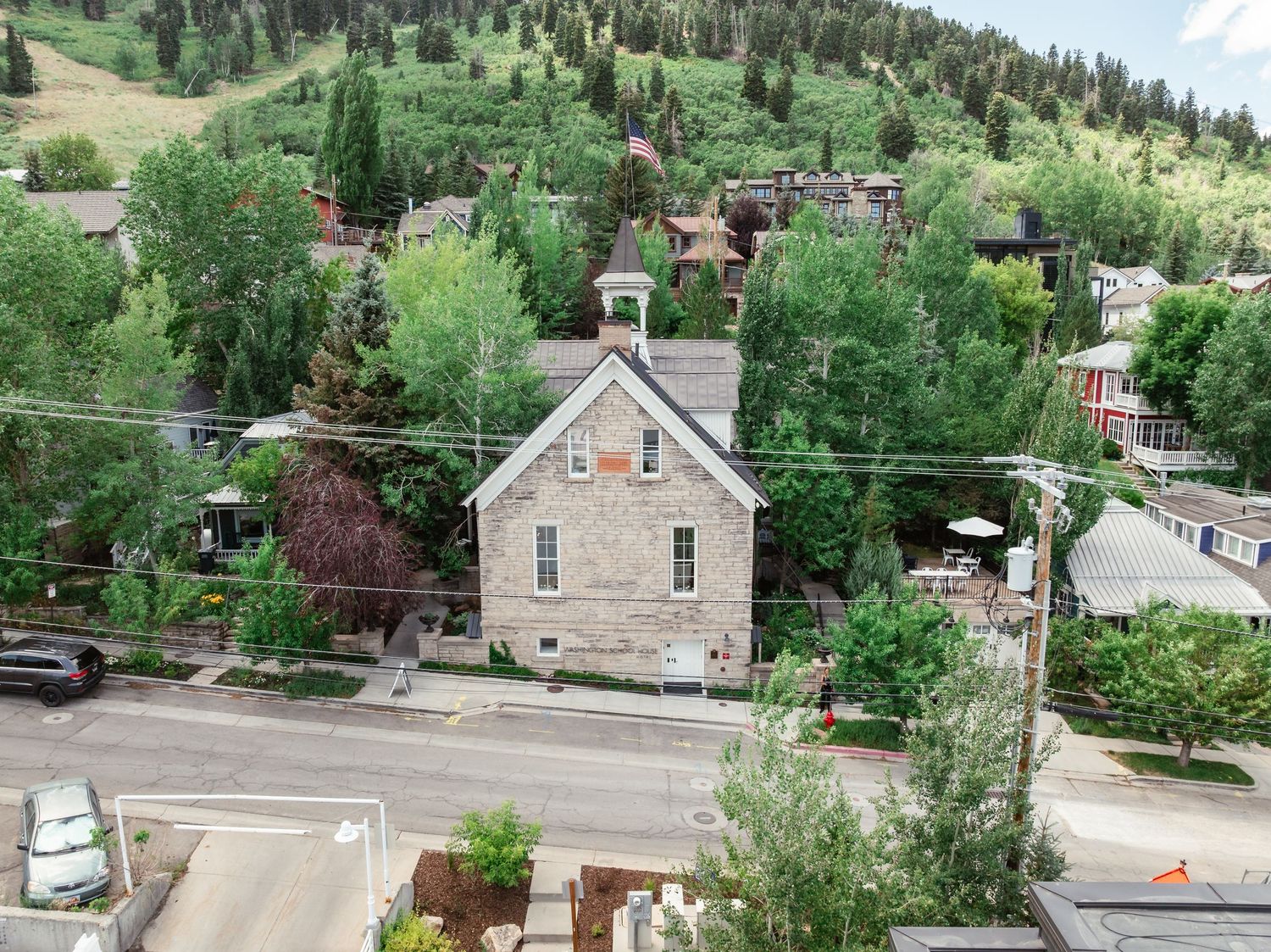 Historic stone church building nestled among trees on a hillside in a mountain town.