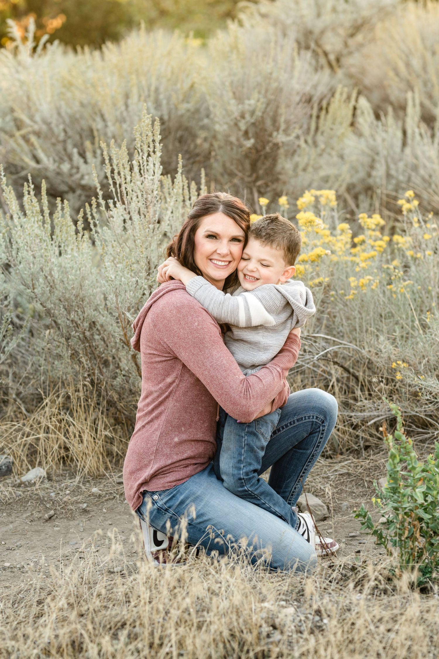 Candid family portrait session showing joyful embraces among loved ones in a natural desert landscape at sunset.