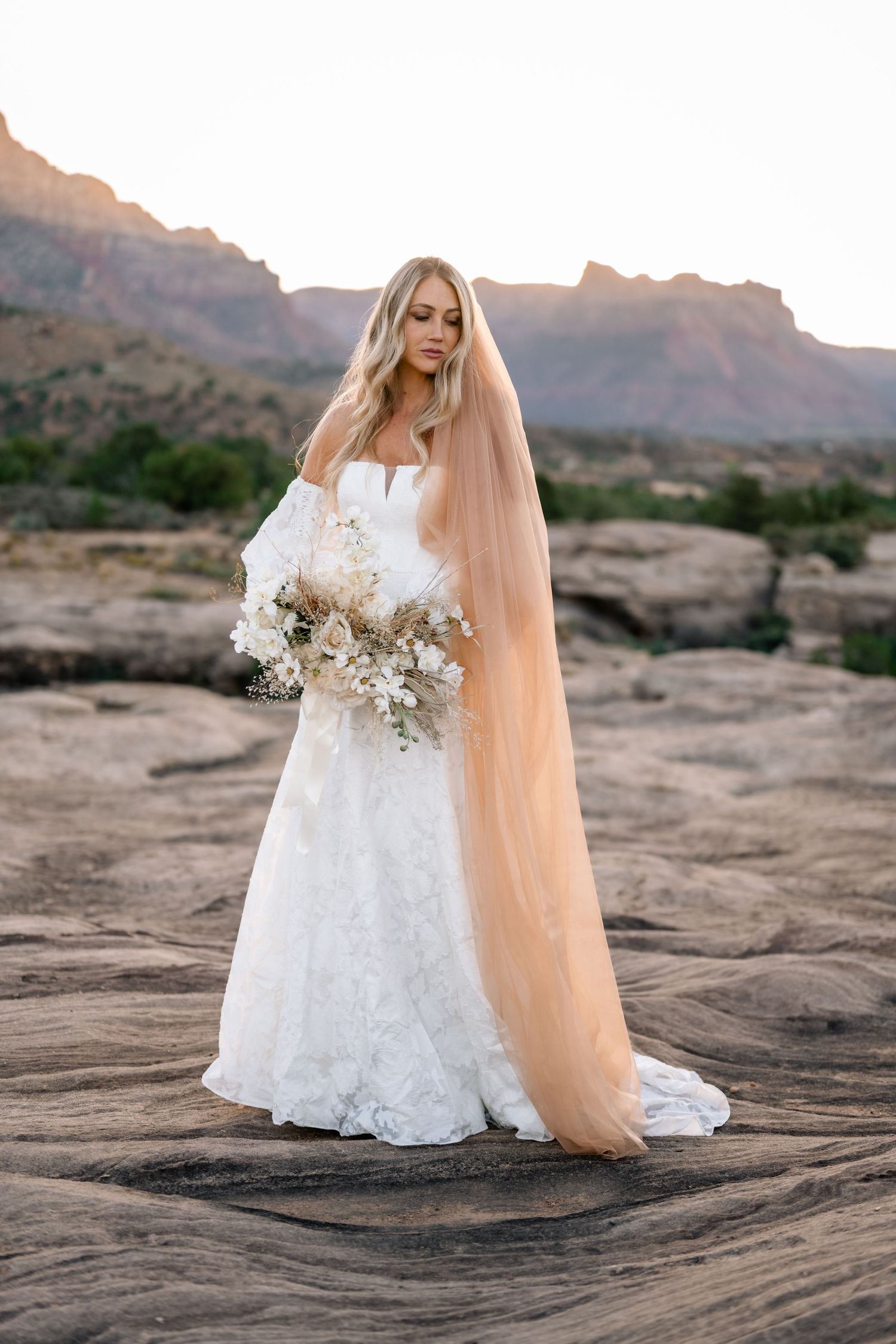 Zions wedding photographer takes beautiful desert sunrise bridals featuring a unique veil and dried floral bouquet.