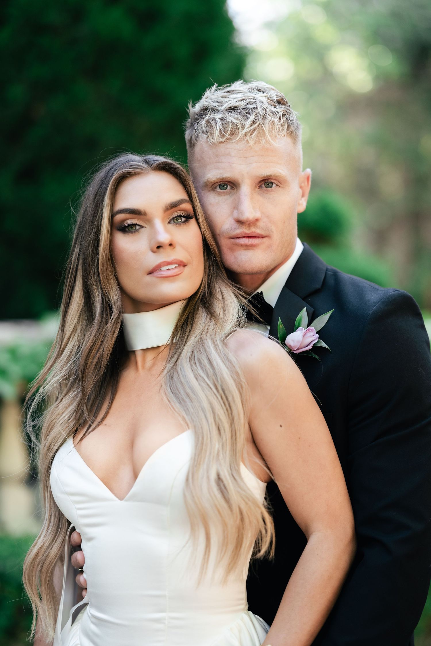 Formal wedding portrait featuring classic black and white attire against garden setting.