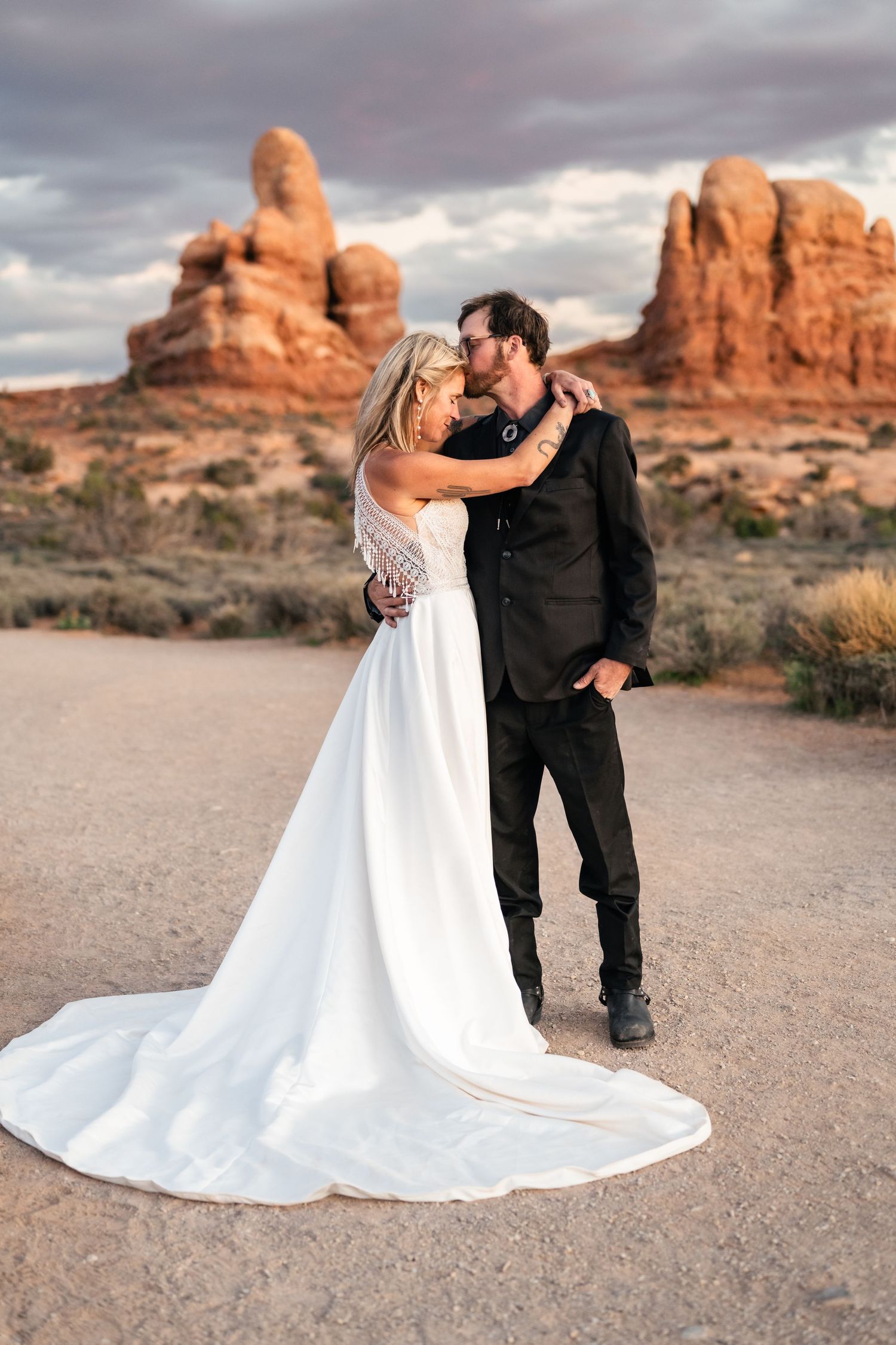 Elope couple gives forehead kiss at Arches National Park with Utah Elopement photographer and videographer