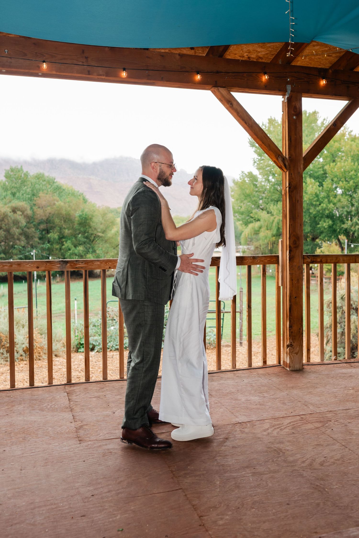 A romantic moment between a couple dancing on a covered wooden deck with mountain views.