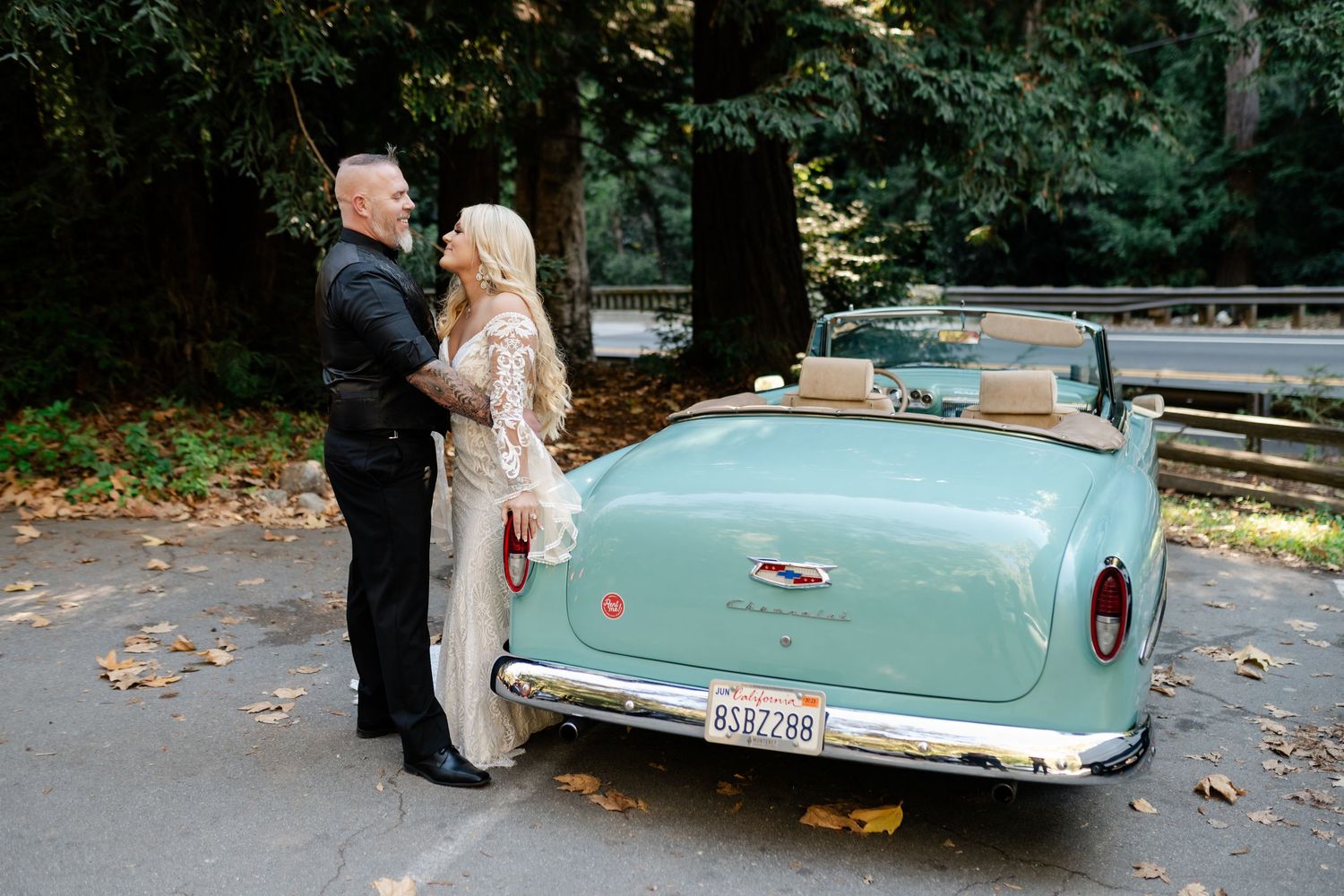 A classic mint green vintage car parked in a wooded area during a wedding photoshoot.