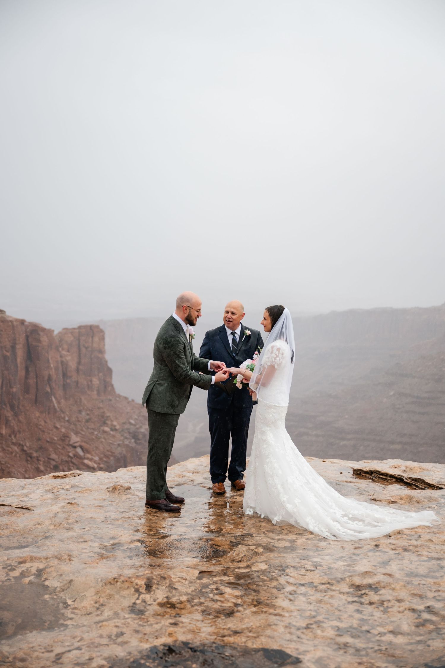 Wedding ceremony on rocky cliff overlooking dramatic canyon landscape.