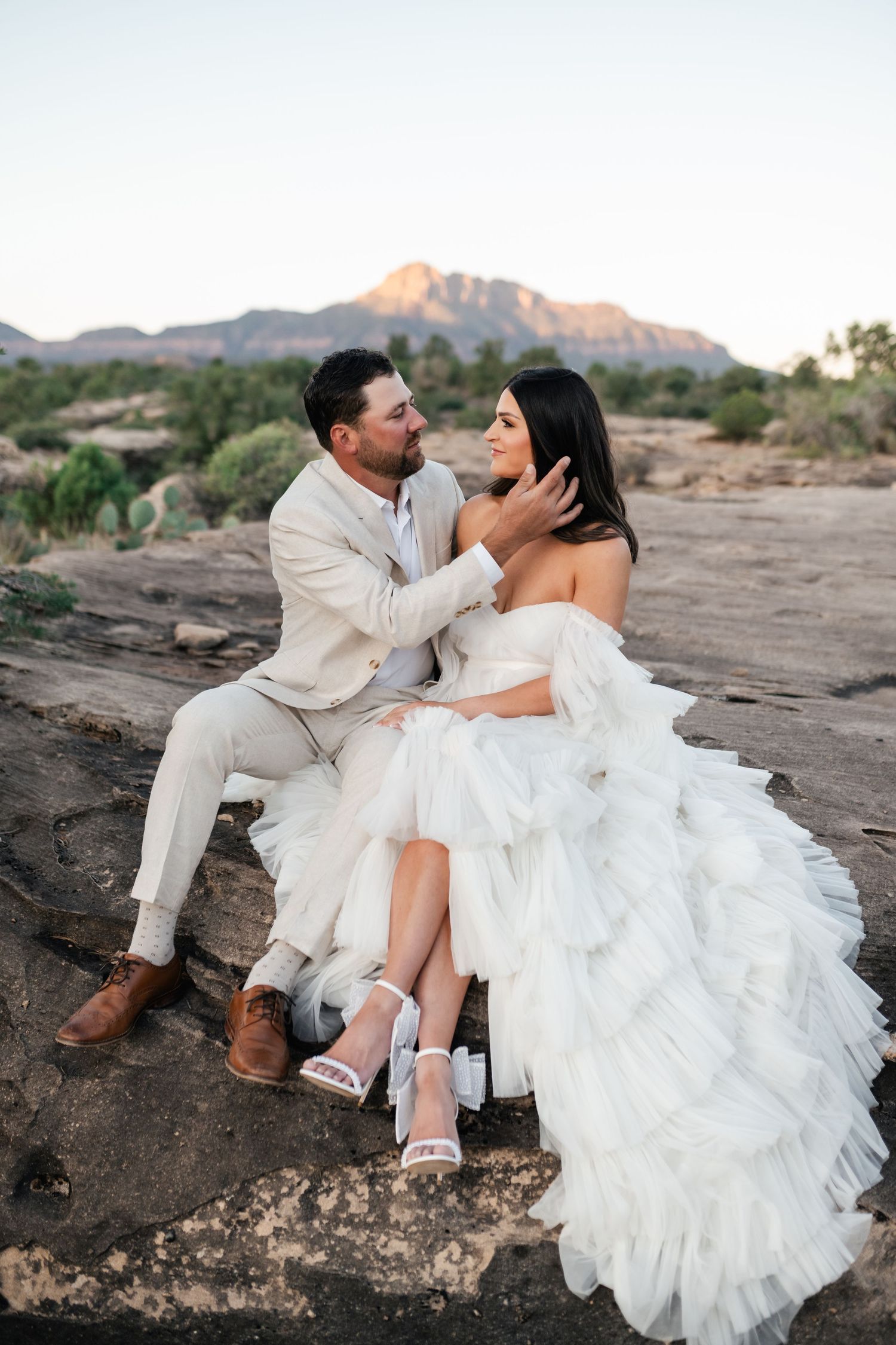 Zion Adventure Session. Newlyweds in white attire share intimate moments on desert rocks during golden hour.