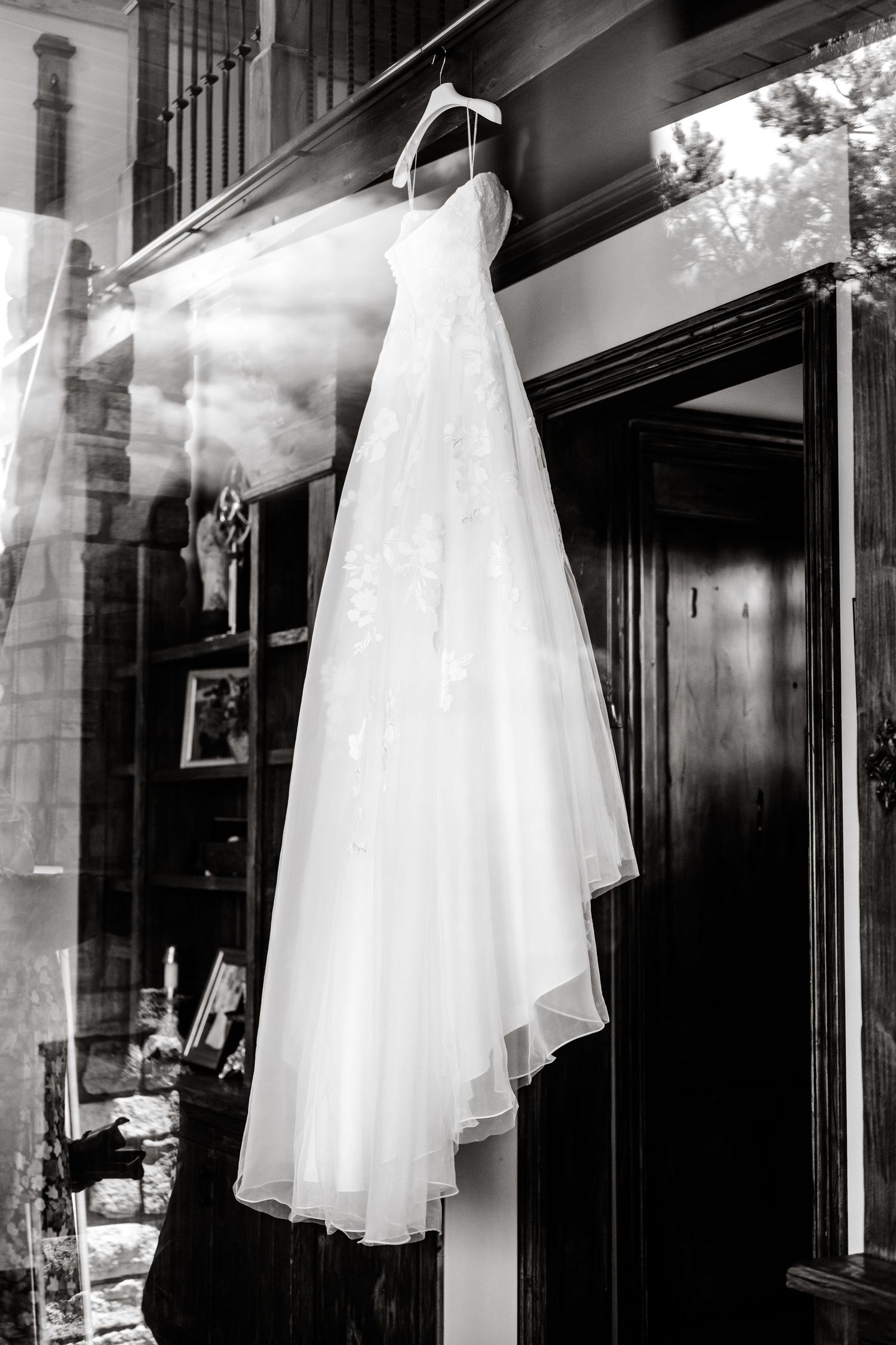 White wedding dress hanging in display window creating elegant silhouette.