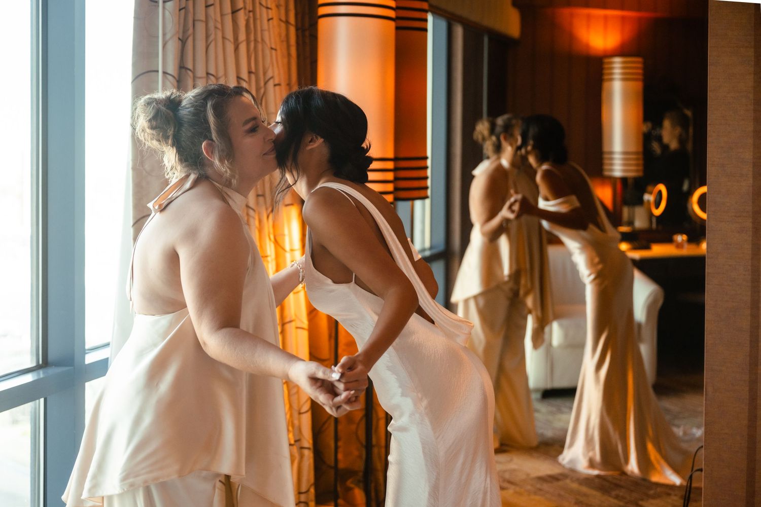 Elegant wedding dress train trailing on marble floor in warm-lit hallway with large windows.
