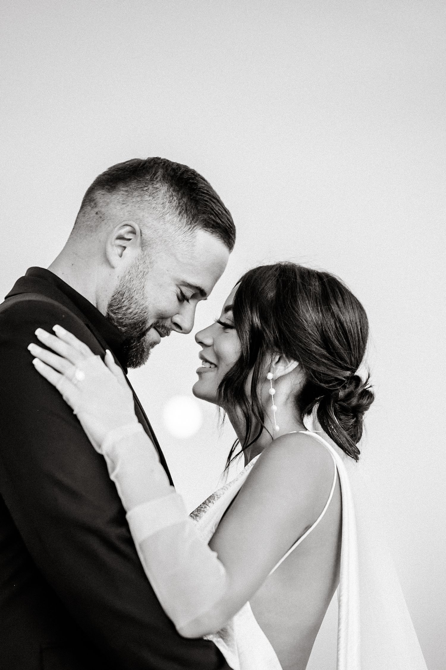An intimate black and white portrait of newlyweds sharing a tender moment.