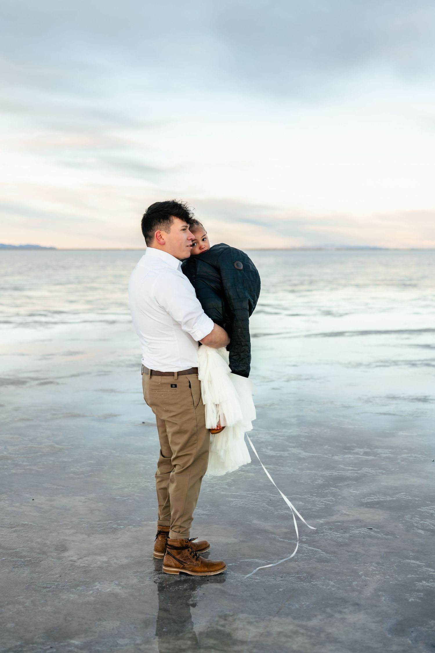 A father and daughter shield against the cold wind of the Salt Flats.