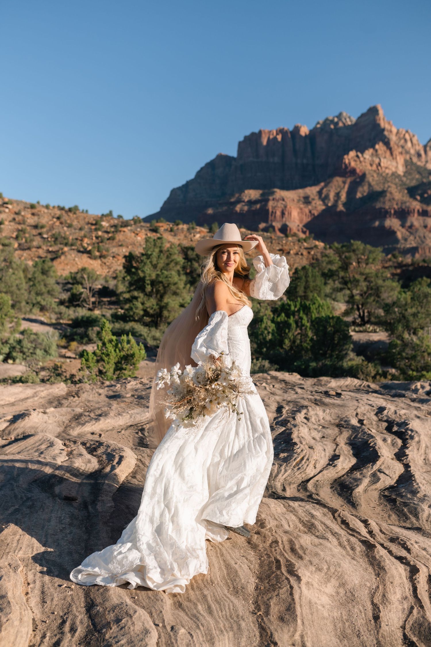 Utah elopement photographer takes breathtaking desert sunrise bridal session with a stunning bouquet and cowgirl hat.